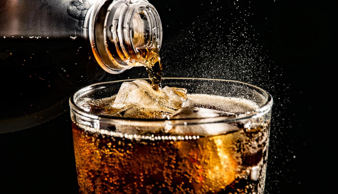 یک لیوان نوشابه مشکی و یخ با پس‌زمینه مشکی