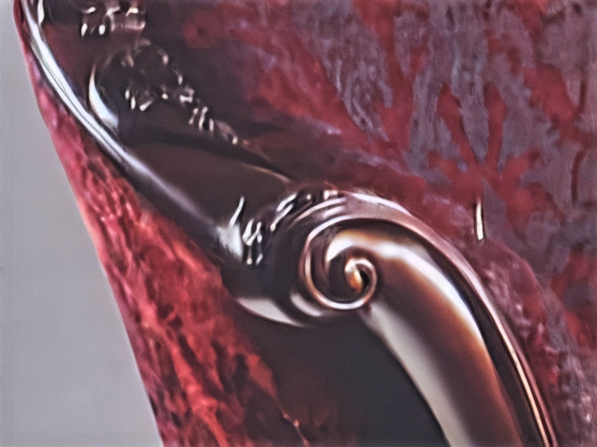 کنده‌کاری روی دسته یک مبل قرمز تک‌نفره