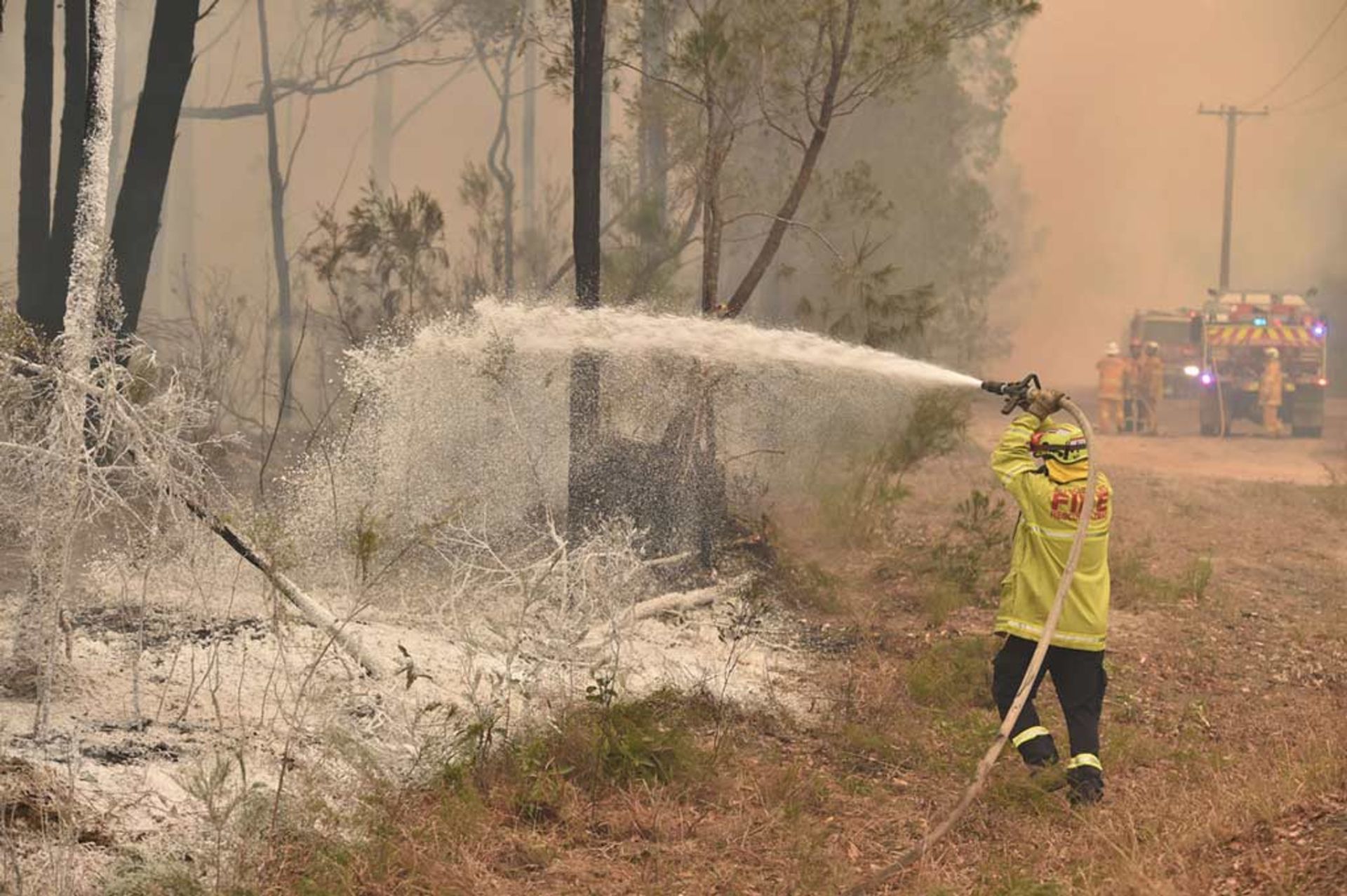 مأمور آتش‌نشانی در حال پاشیدن اسپری ضد حریق