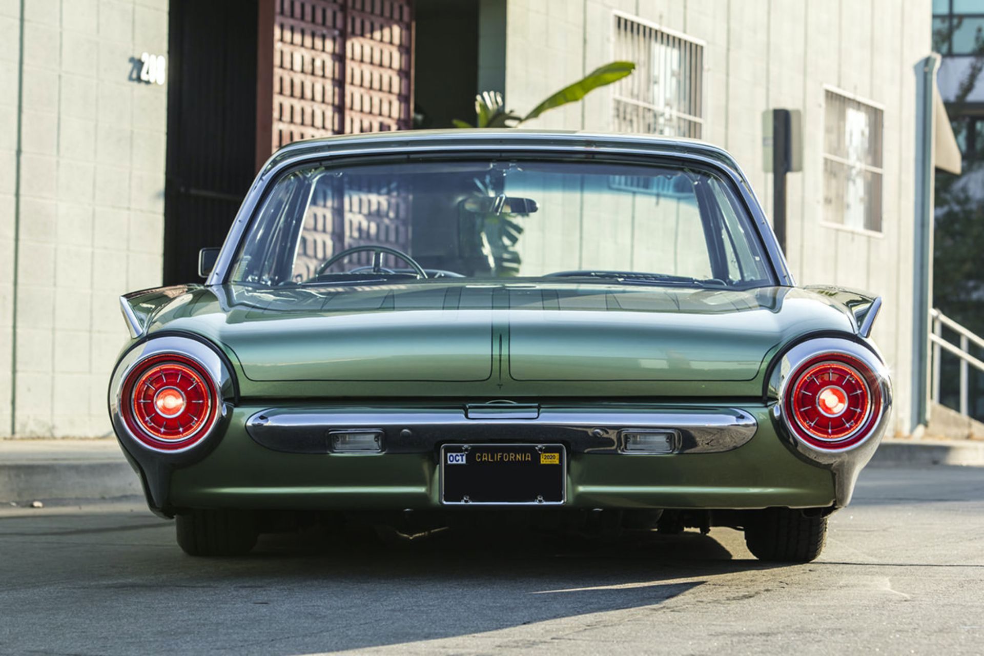 نمای عقب خودرو کلاسیک فورد تاندربرد / 1963 Ford Thunderbird سبز رنگ در کنار ساختمان