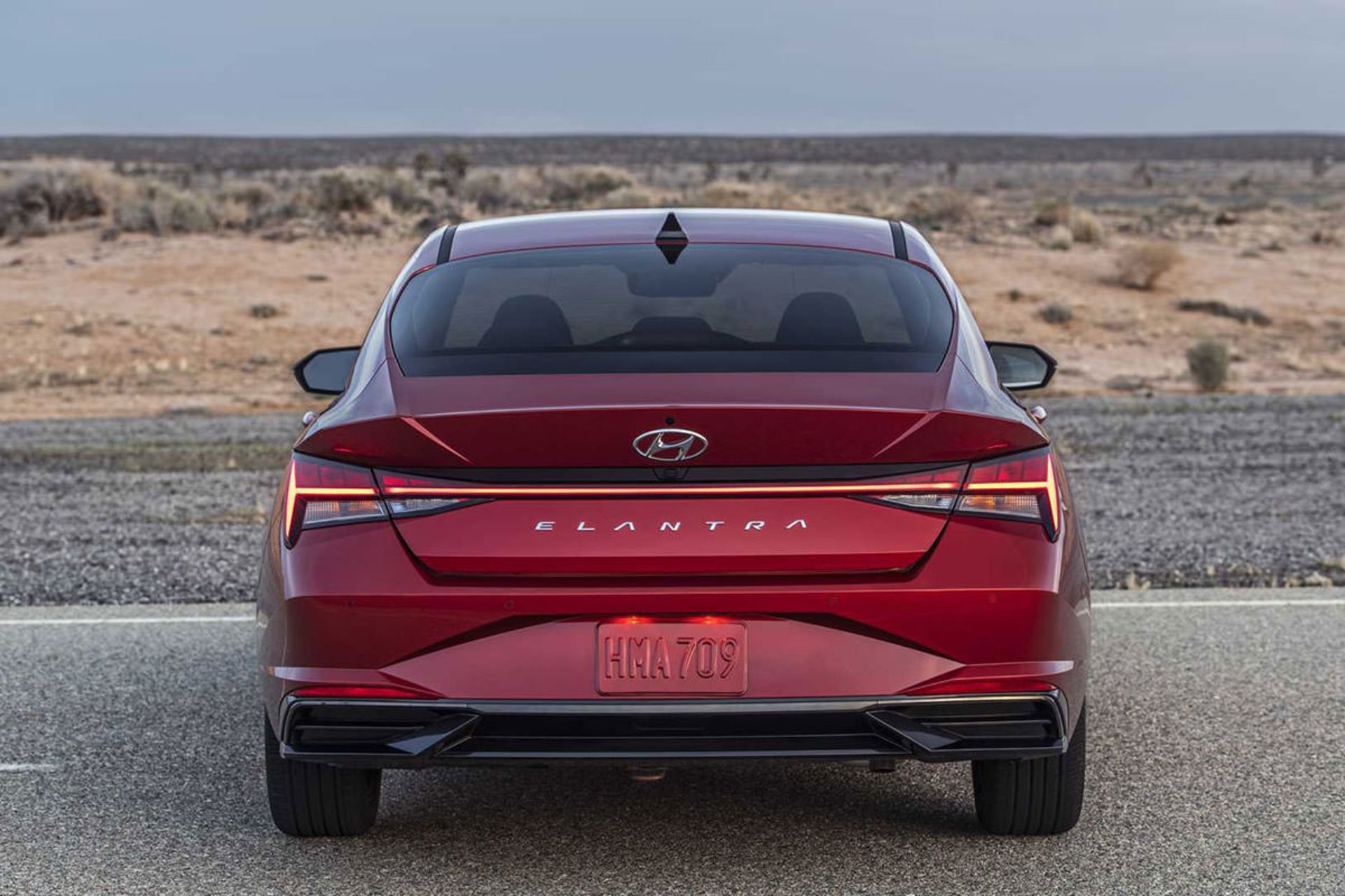 نمای عقب هیوندای النترا 2021 / 2021 Hyundai Elantra قرمز رنگ با منظره آسمان ابری