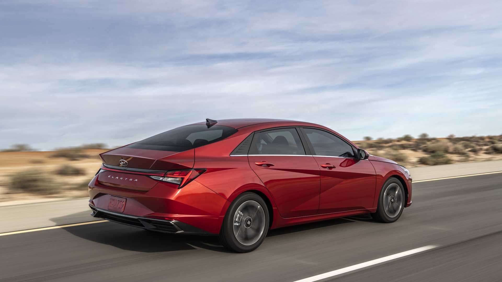 نمای سه چهارم عقب هیوندای النترا 2021 / 2021 Hyundai Elantra قرمز رنگ با منظره آسمان ابری