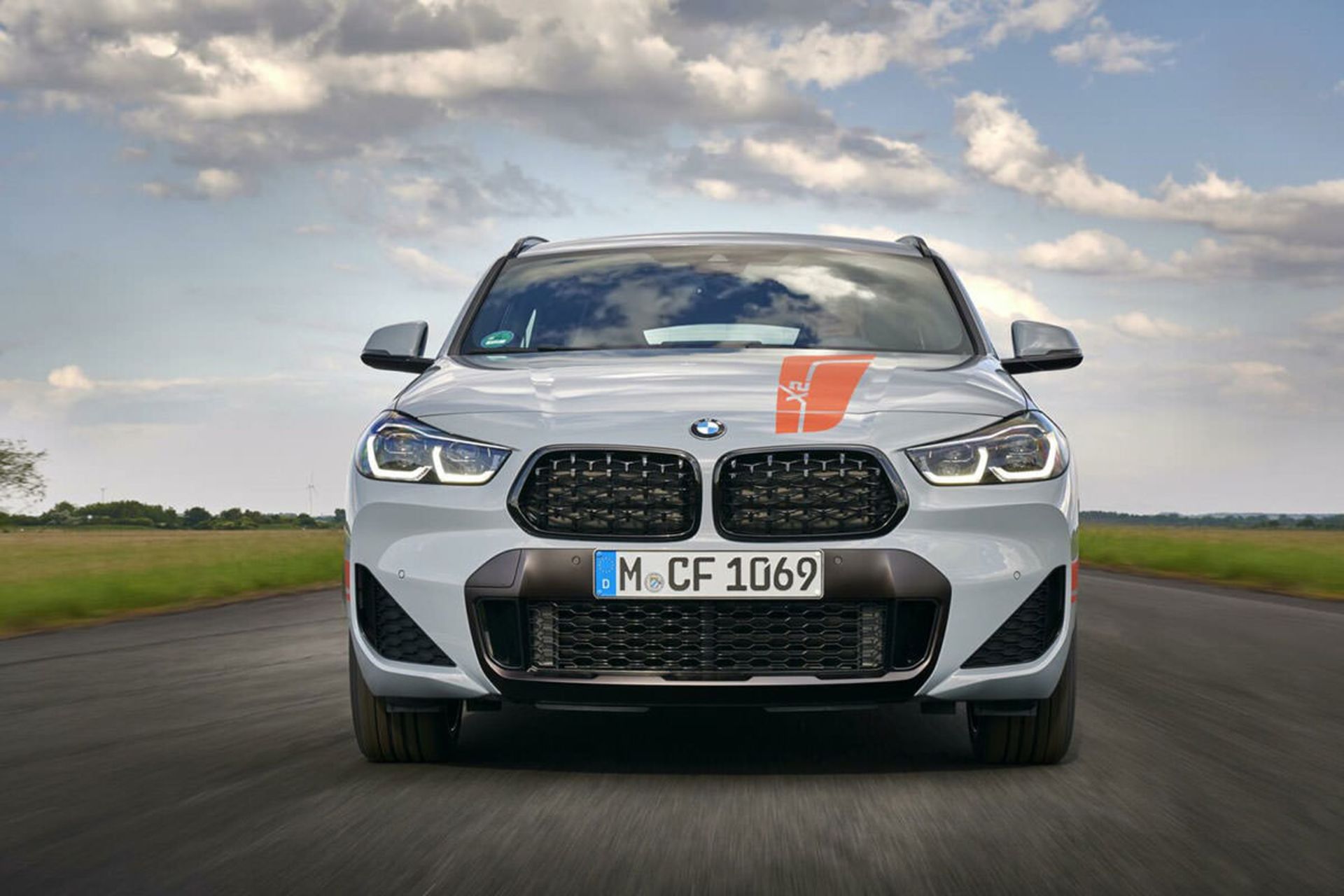 نمای جلو کراس اور بی ام و ایکس 2 / BMW X2 M Mesh Edition نقره ای رنگ با منظره آسمان ابری در جاده