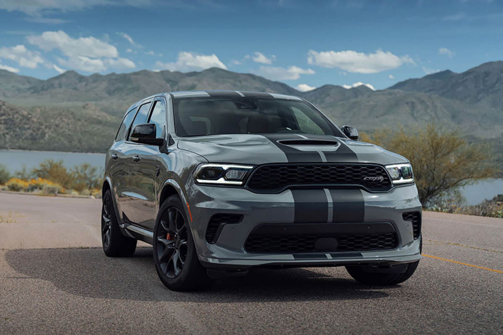 نمای سه چهارم چپ شاسی بلند هنسی دوج دورانگو اس آر تی هل کت / Hennessey Dodge Durango SRT Hellcat با منظره آسمان و ابر و کوه