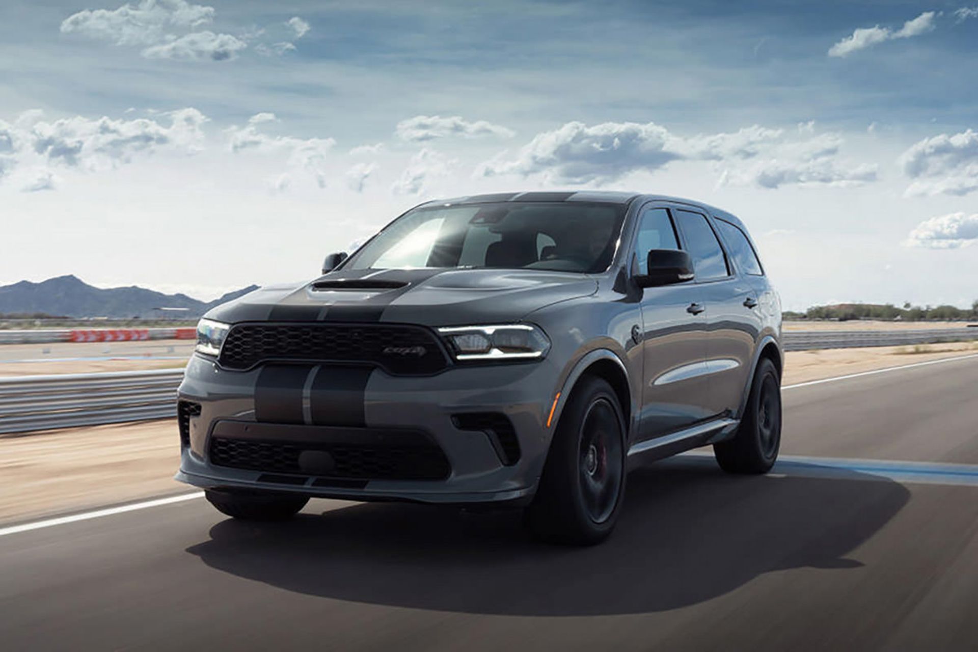 نمای سه چهارم شاسی بلند هنسی دوج دورانگو اس آر تی هل کت / Hennessey Dodge Durango SRT Hellcat در جاده با منظره آسمان ابری