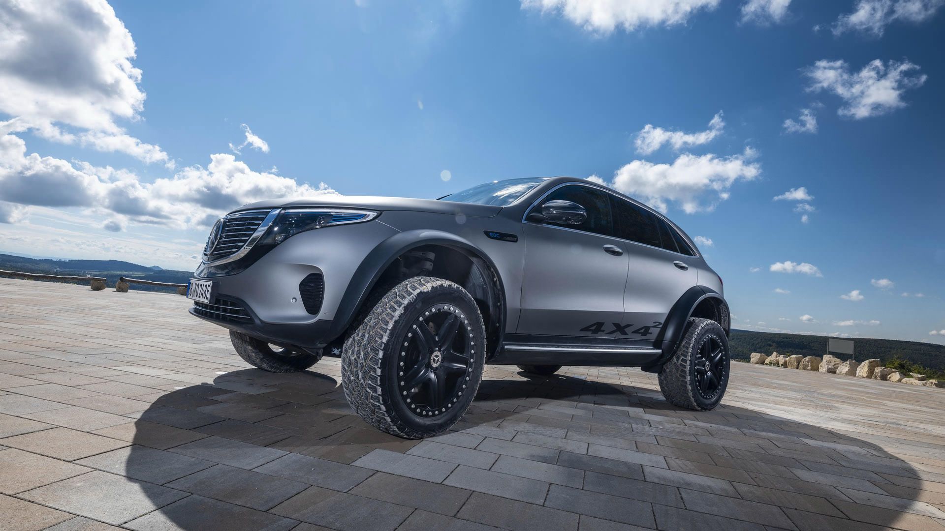 نمای سه چهارم جلو مدل مفهومی و شاسی بلند برقی مرسدس بنز / Mercedes-Benz EQC 4×4² نقره ای رنگ با منظره آسمان ابری
