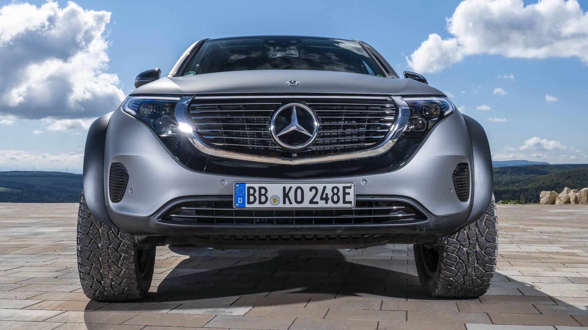 نمای جلو خودروی مفهومی و شاسی بلند برقی مرسدس بنز / Mercedes-Benz EQC 4×4² نقره ای رنگ در مسیر آفرود با منظره آسمان