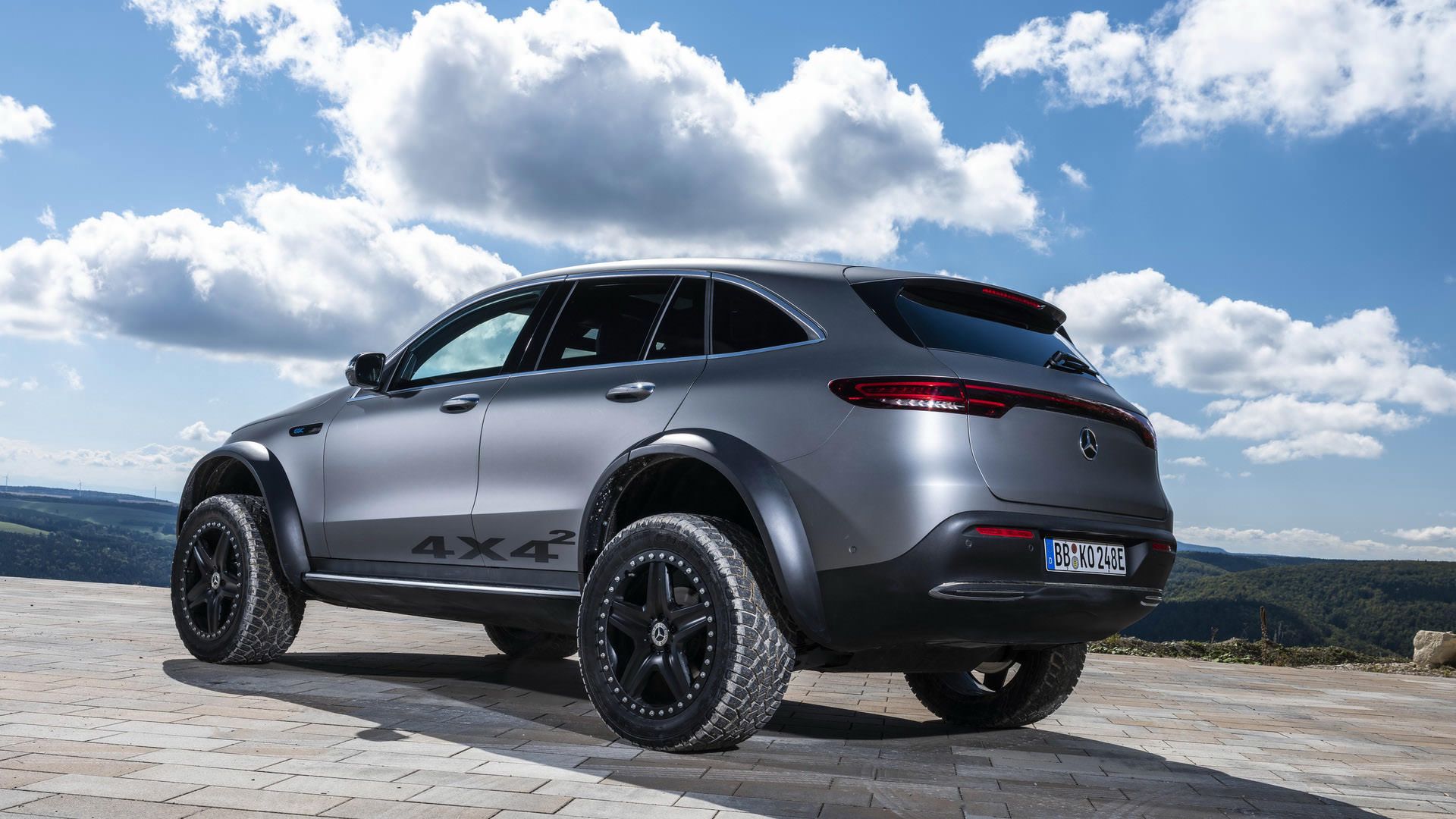 نمای عقب خودروی مفهومی و شاسی بلند برقی مرسدس بنز / Mercedes-Benz EQC 4×4² نقره ای رنگ با منظره آسمان ابری