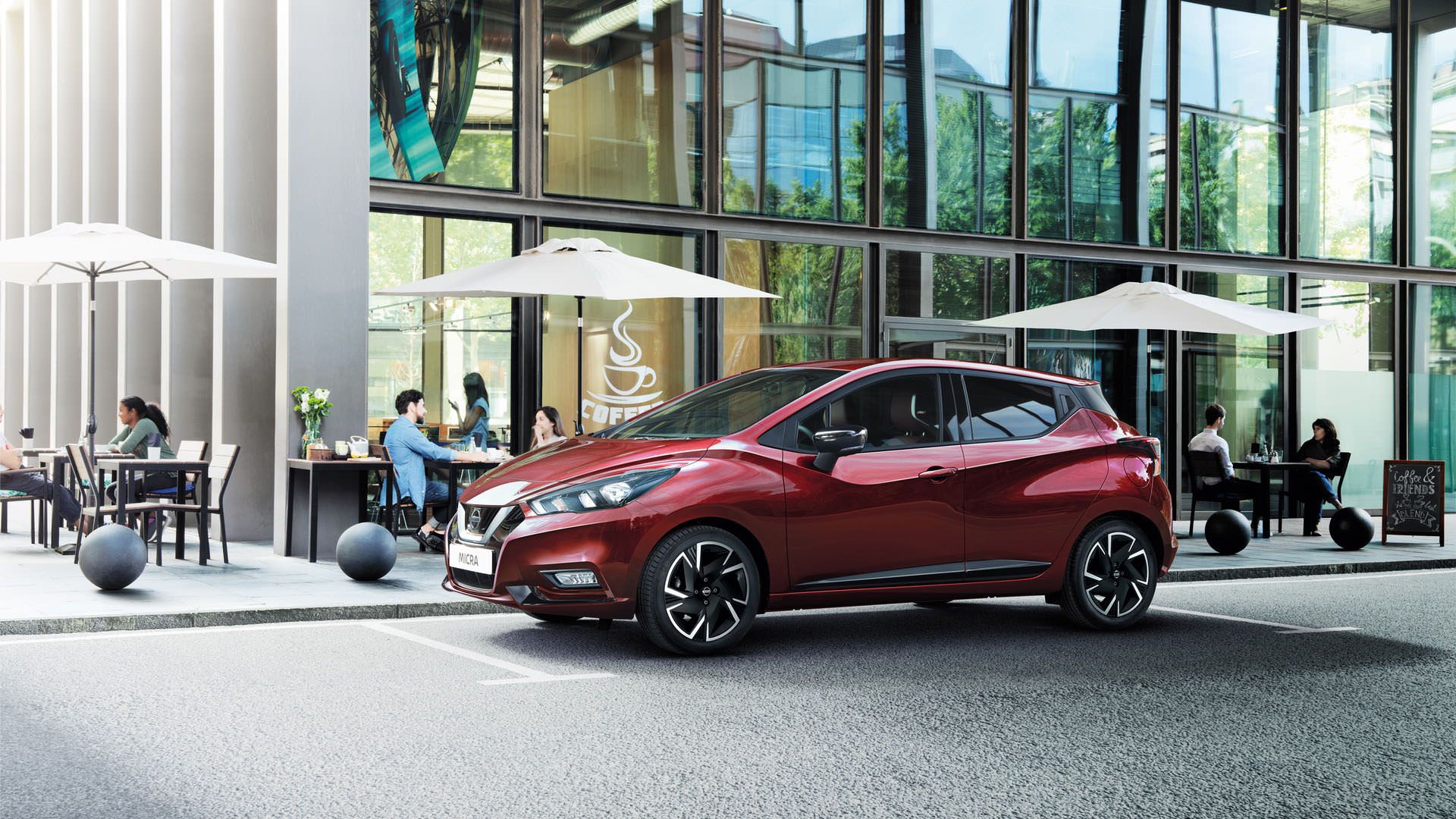 نمای جانبی هاچ بک / hatchback نیسان میکرا / 2021 Nissan Micra مدل 2021 قرمز رنگ در کنار ساختمان