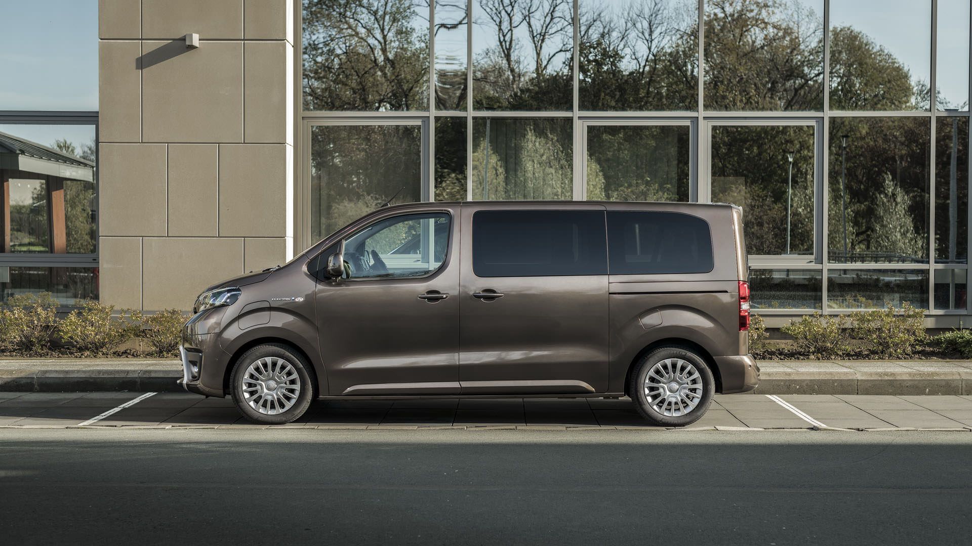 نمای جانبی ون الکتریکی تویوتا پروسه ورسو / 2021 Toyota Proace Verso در کنار ساختمان