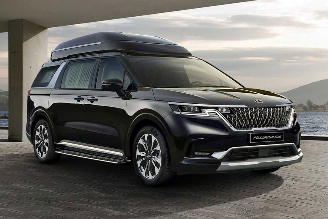 نمای جلو مینی ون کیا کارنیوال 2021 / 2021 Kia Carnival سیاه رنگ در کنار ساختمان