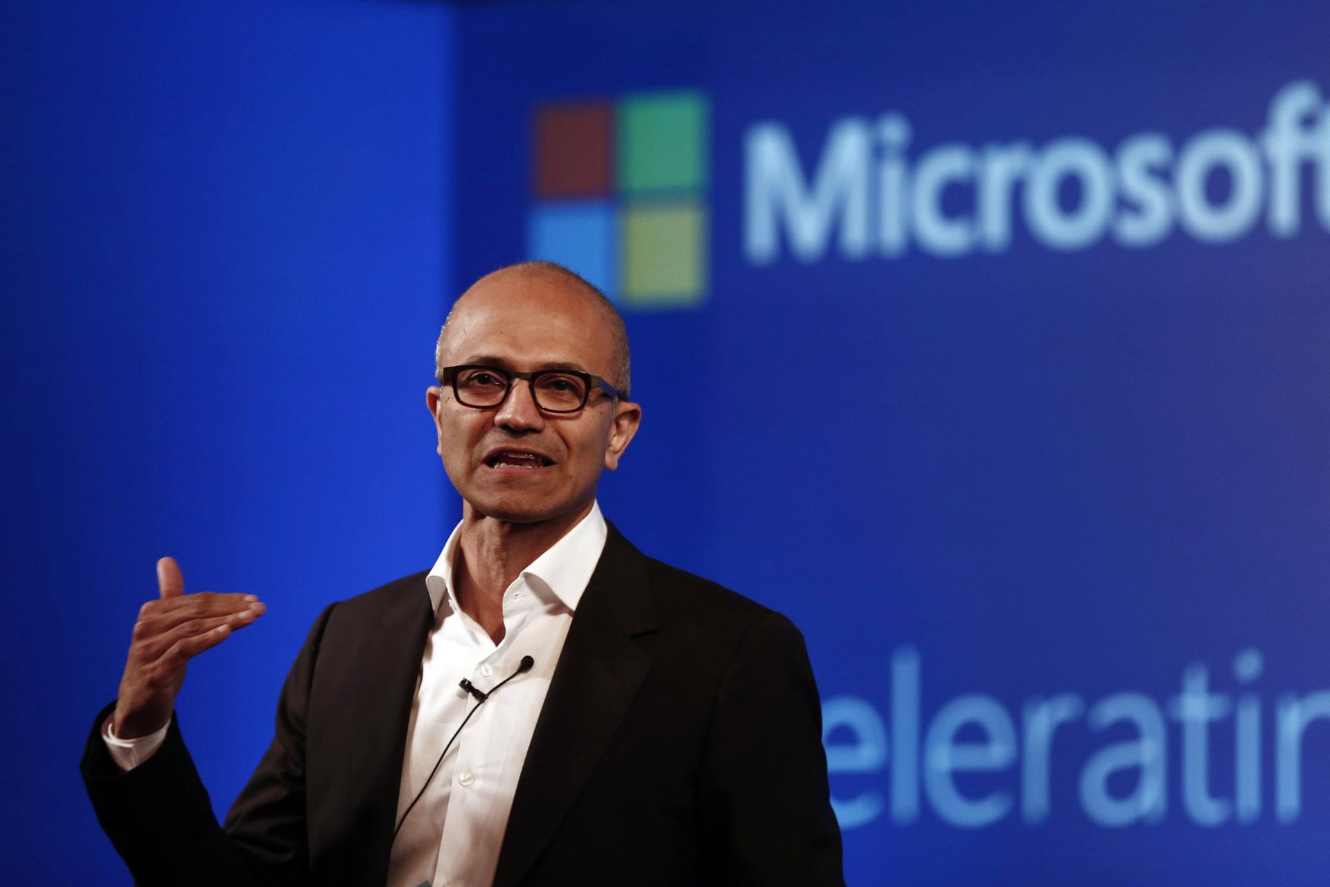 ساتیا نادلا / Satya Nadella مدیرعامل مایکروسافت در حال سخنرانی لوگوی مایکروسافت در پشت سر