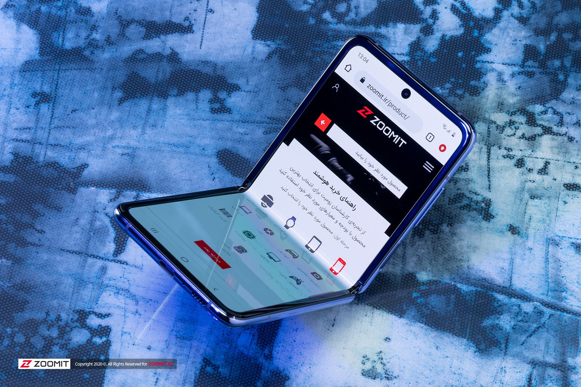 سایت زومیت روی گلکسی زد فلیپ سامسونگ / Galaxy Z flip در حالت نیمه باز روی میز