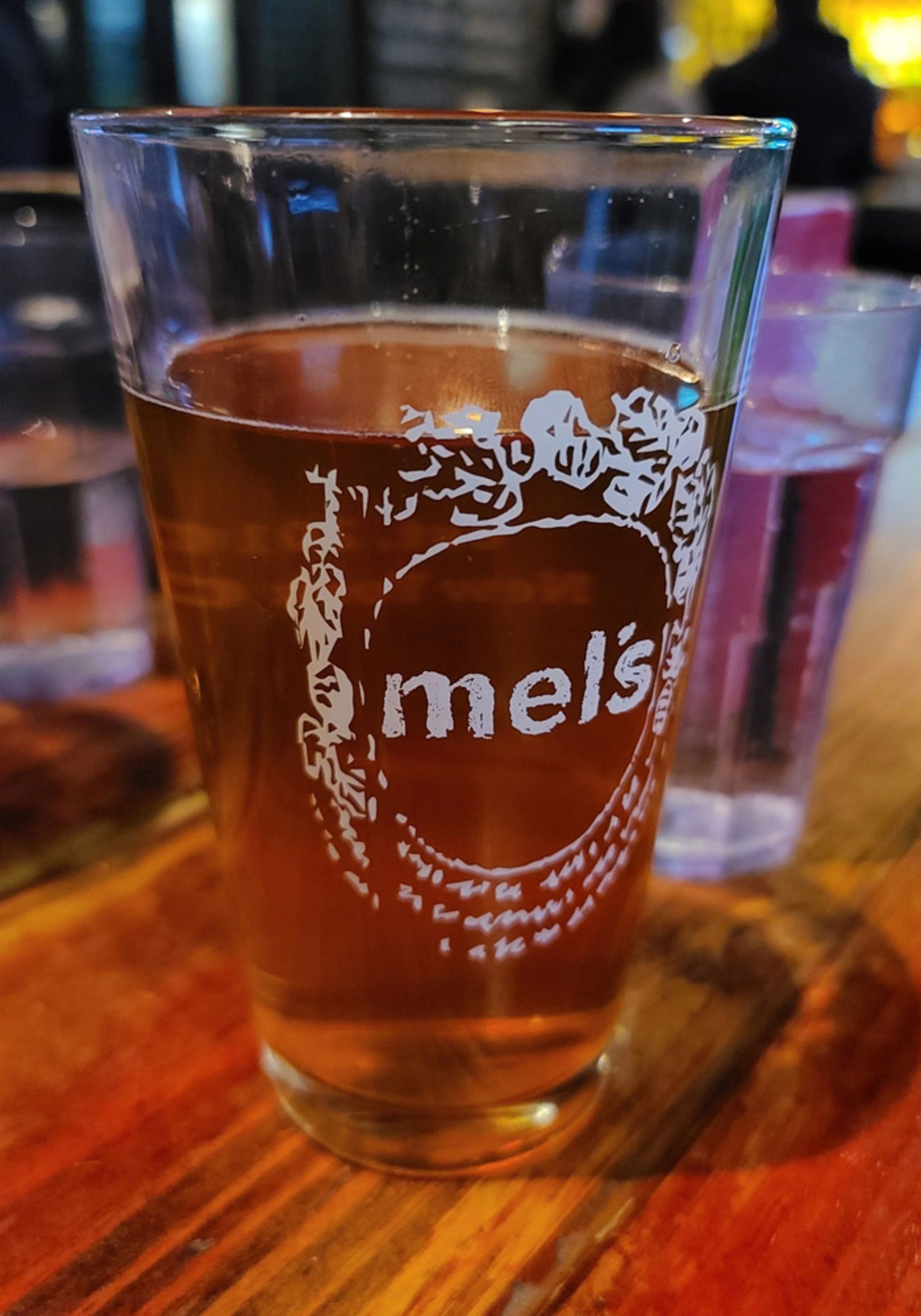 عکس لیوان شیشه‌ای آبجو روی پیشخوان چوبی بار با گوشی گلکسی S20 Ultra