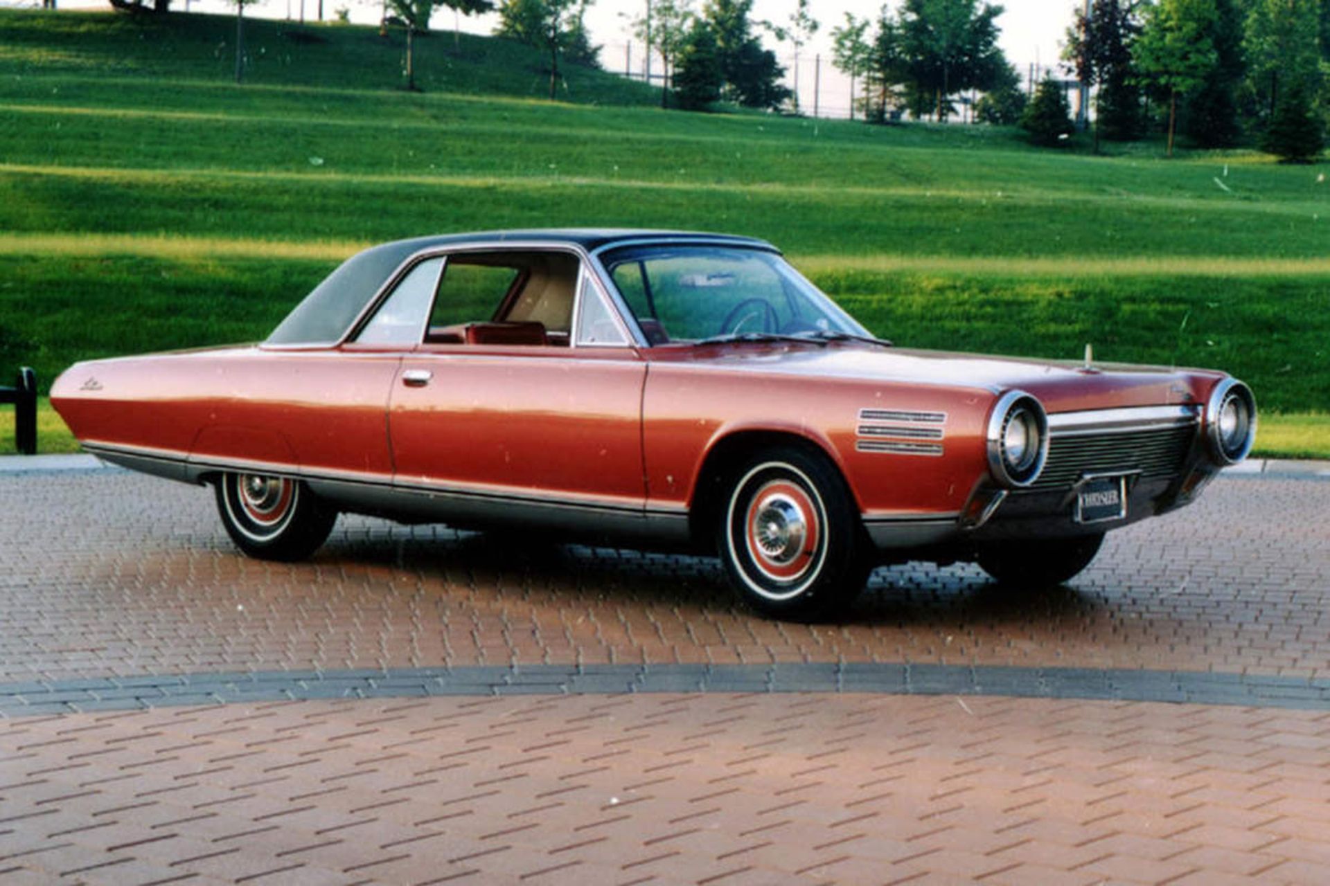 خودرو کلاسیک قرمز رنگ در پارک با پس زمینه سبز و درخت 