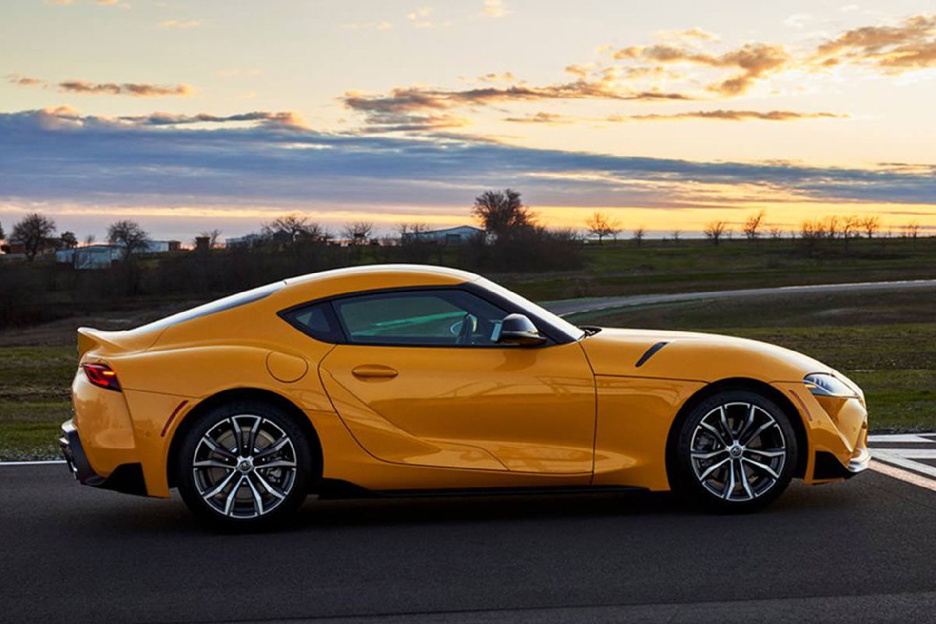 تویوتا سوپرا ۲۰۲۱ با رنگ زرد و رینگ‌های زیبا در صحنه‌ی غروب و طبیعت زیبا در پیست مسابقه