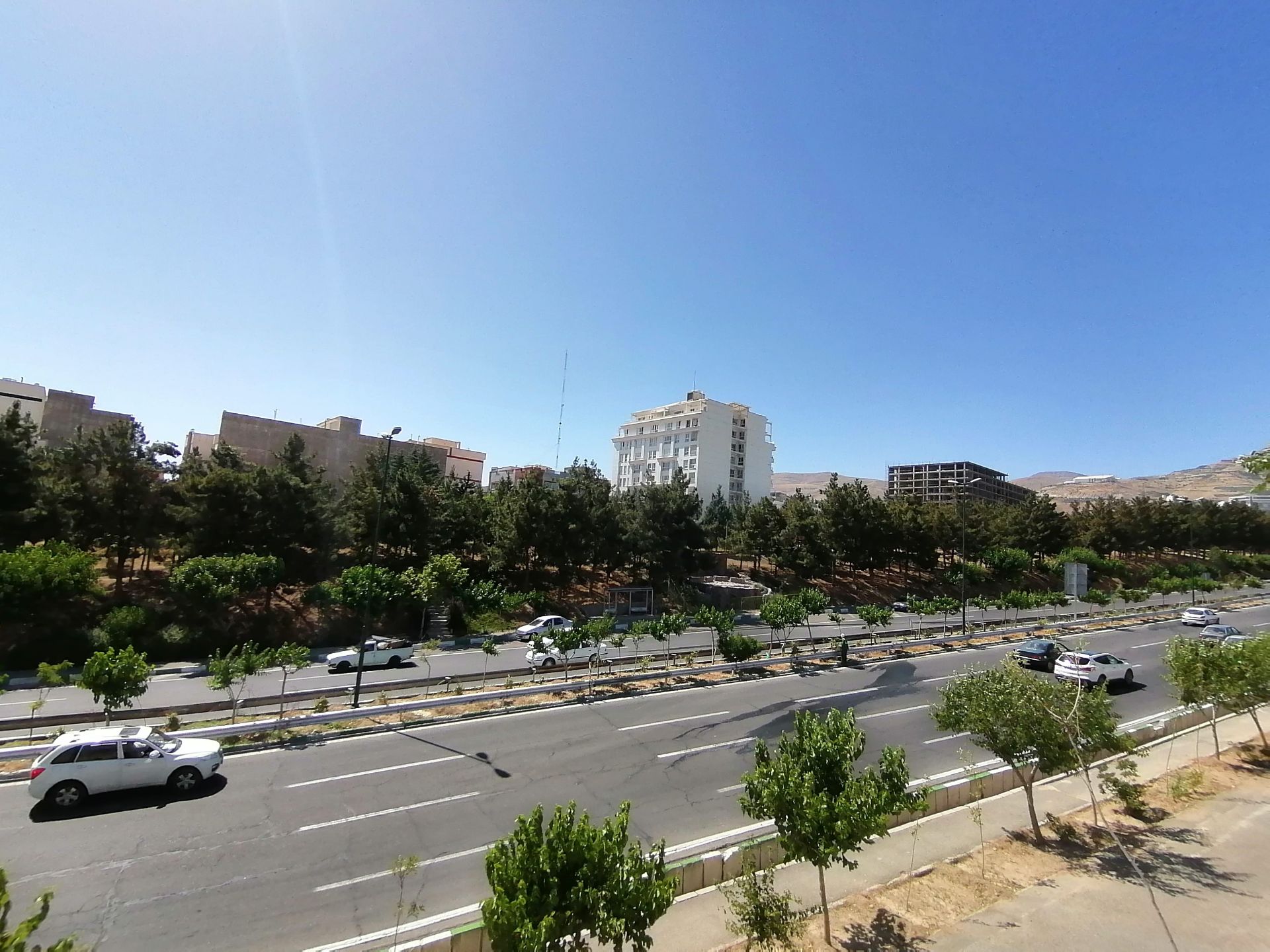 عکس اولتراواید از ساختمان‌ها و درختان کنار بزرگراه به همراه خودروهای در حال حرکت