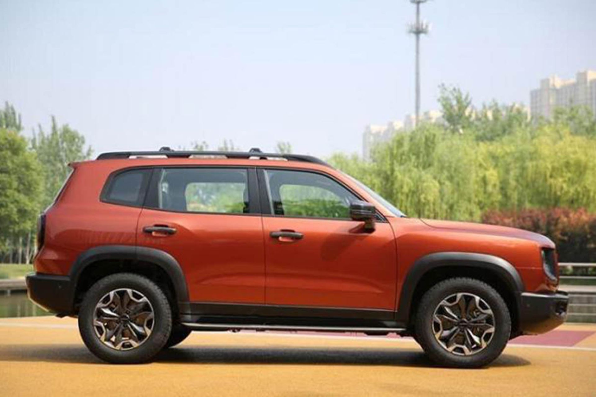 نمای جانبی خودرو شاسی بلند هاوال بیگ داگ / Haval DaGou SUV در کنار درخت و آسمان آبی 