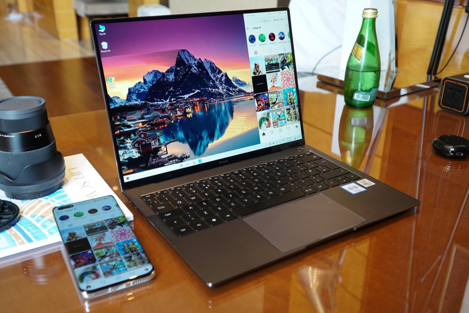 میت بوک ایکس پرو 2020 هواوی ازنمای کنار روی میز با گوشی و لنز دوربین و نوشیدنی