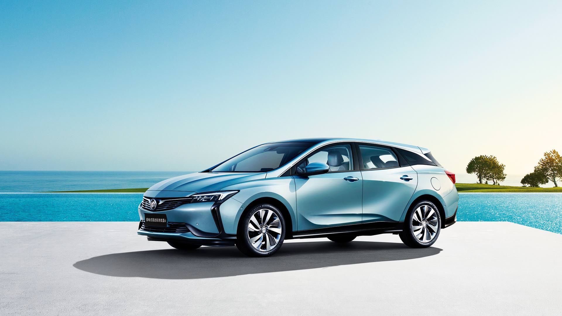 خودروی پلاگین هیبریدی / hybrid car بیوک ویلایت 6 / buick velite 6 آبی رنگ با زمینه دریا و درخت