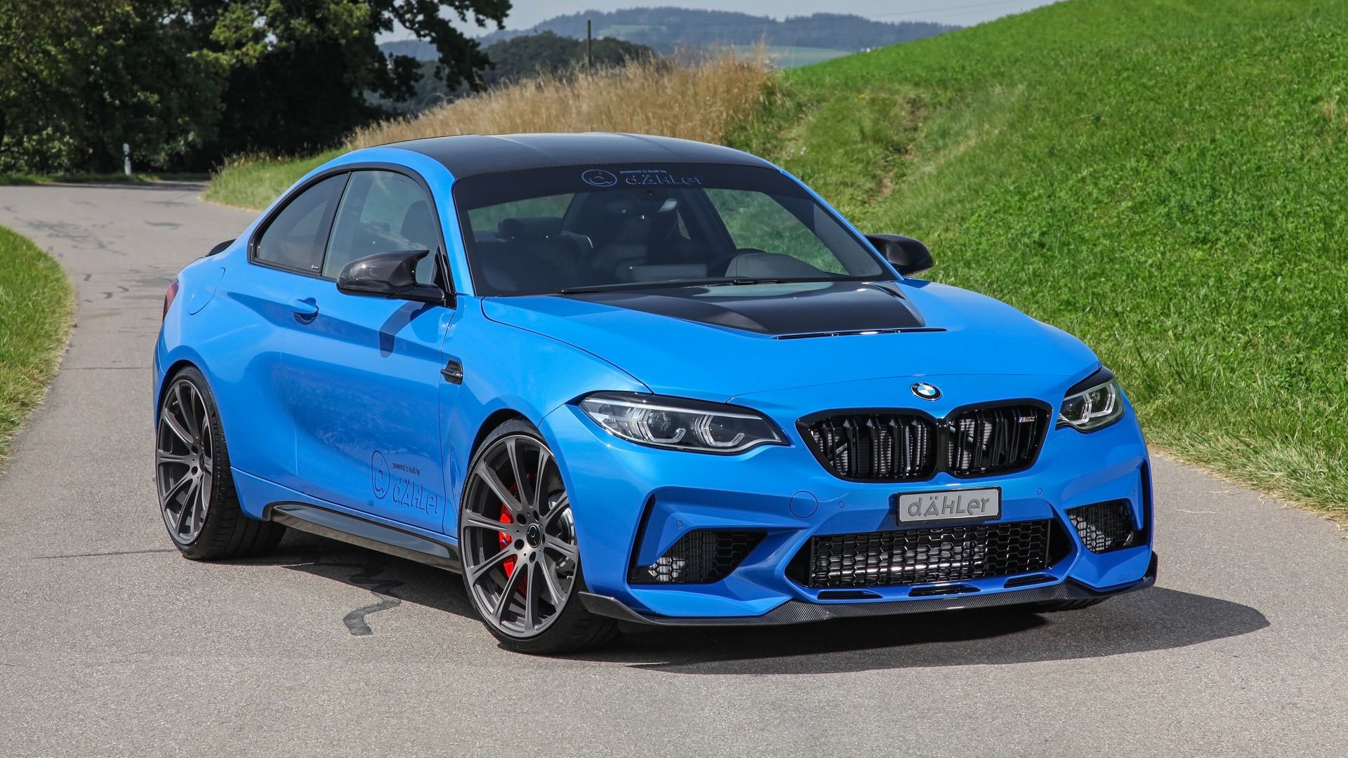 خودرو بی ام و ام 2 سی اس / Dahler BMW M2 CS آبی رنگ با تیونینگ داهلر  در کنار منظره طبیعت سبز