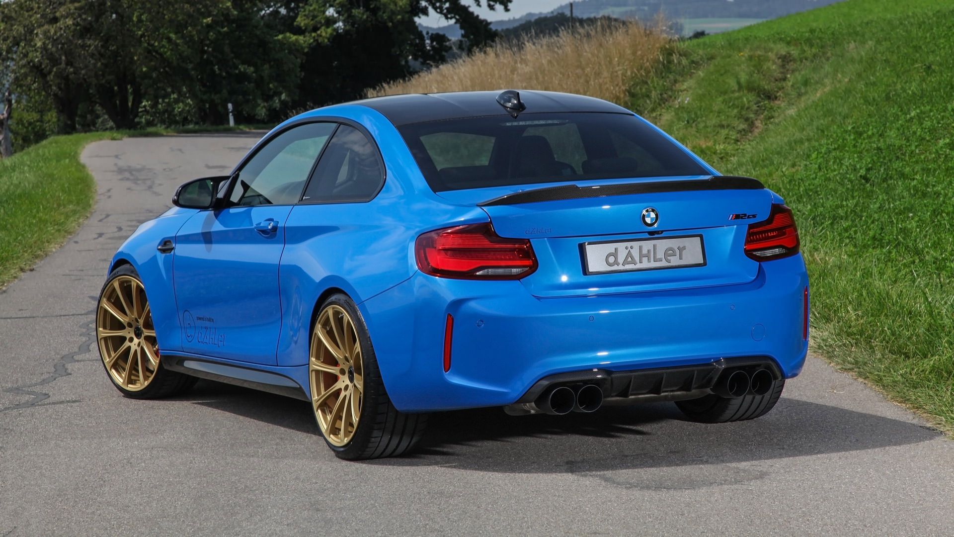 نمای عقب خودرو بی ام و ام 2 سی اس / Dahler BMW M2 CS آبی رنگ با تیونینگ داهلر در کنار سبزه و علف