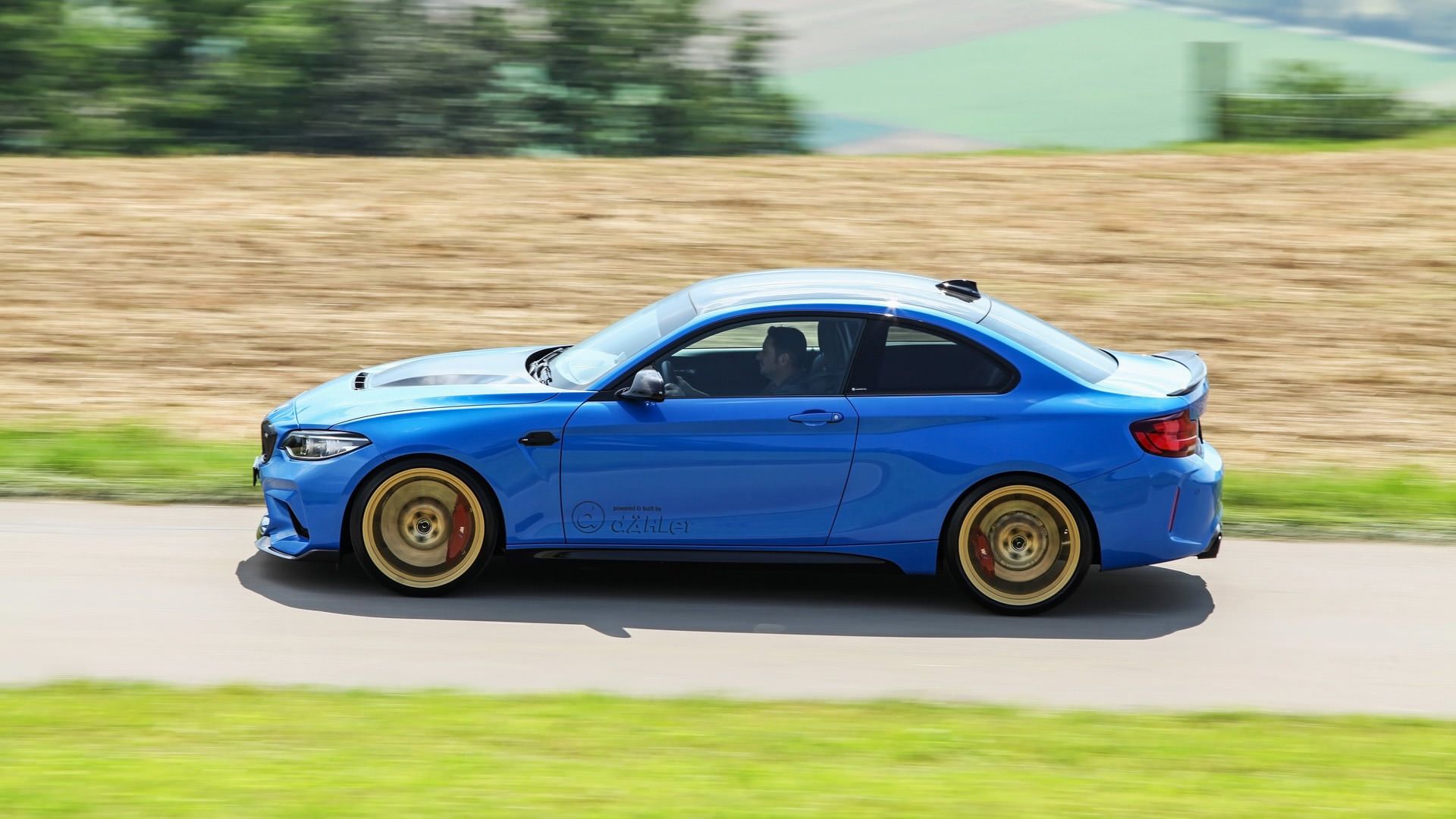 نمای کناری خودرو بی ام و ام 2 سی اس / Dahler BMW M2 CS آبی رنگ با تیونینگ داهلر  در طبیعت سبز