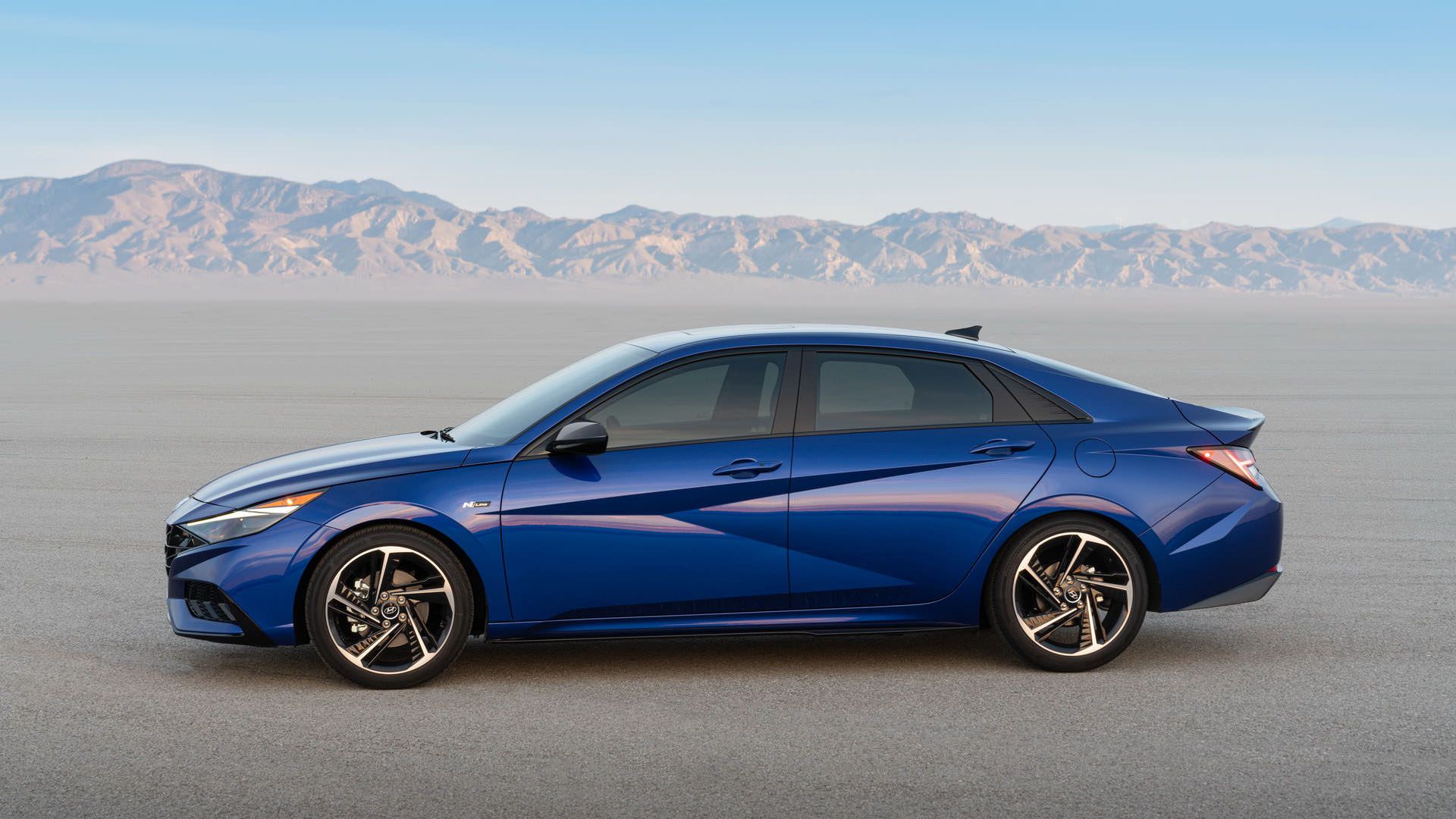 نمای جانبی خودرو سدان هیوندای النترا ان لاین / 2021 Hyundai Elantra N Line آبی رنگ در جاده با آسمان آبی و دشت