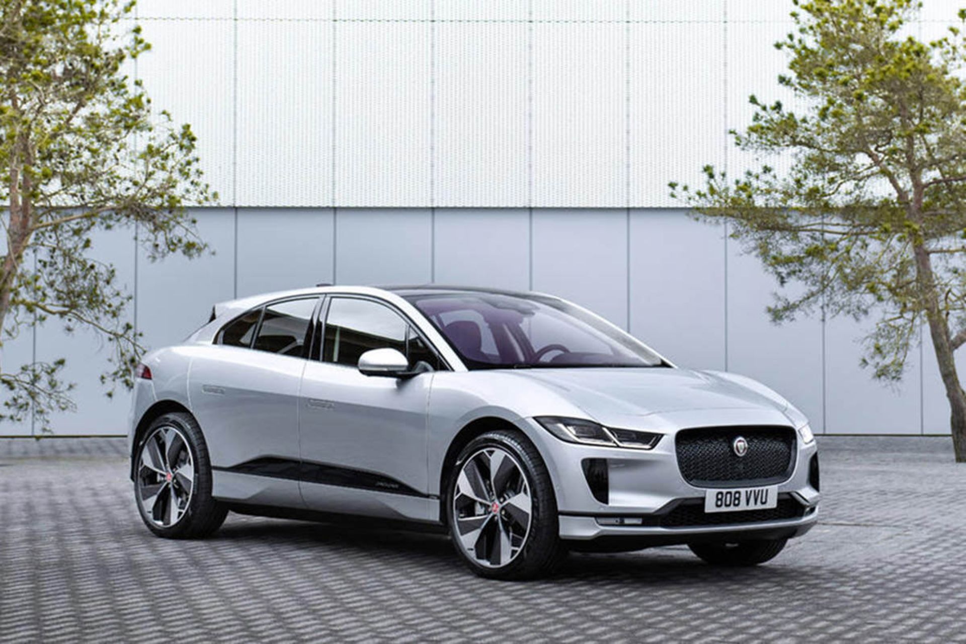 خودروی الکتریکی جگوار آی پیس / jaguar i-pace نقره ای رنگ در کنار دیوار و درخت 