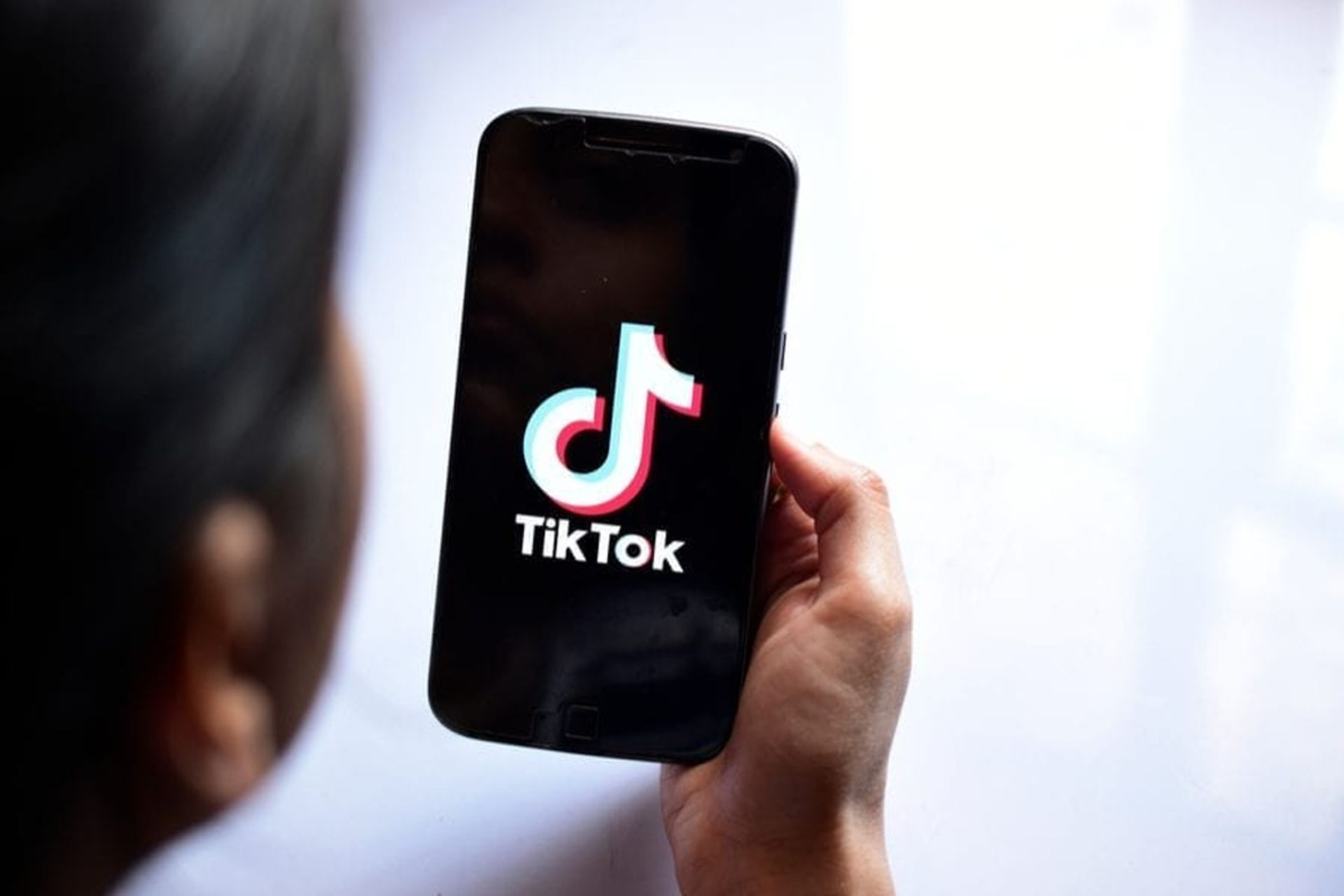 گوشی هوشمند درحال اجرای تیک تاک / TikTok در دست راست یک فرد