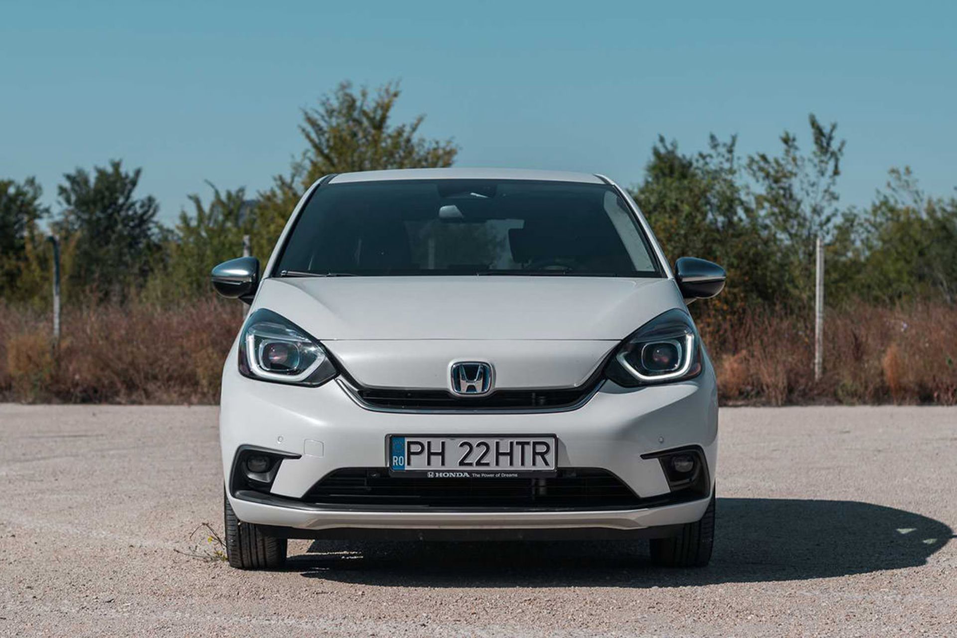 نمای جلو خودروی هیبریدی / Hybrid car هوندا جاز فیت / 2020 Honda Jazz (Fit) e:HEV سفید رنگ با منظره درخت