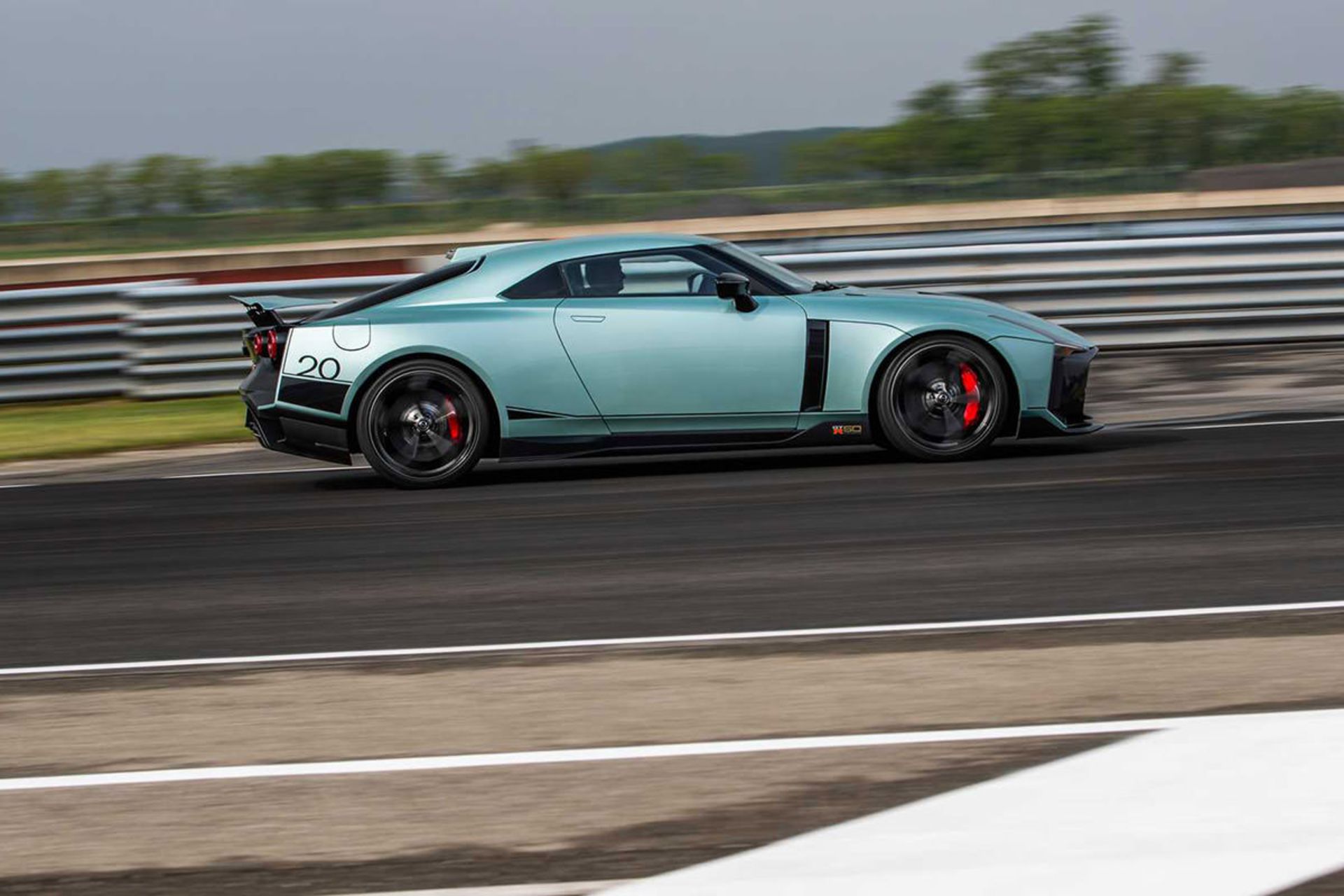 نمای جانبی خودرو اسپرت نیسان جی تی آر 50 / Nissan GT-R50 در پیست با منظره آسمان ابری