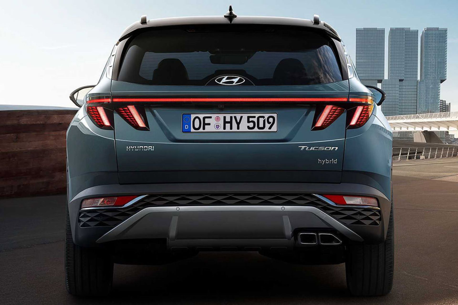 نمای عقب خودرو کراس اور هیوندای توسان 2022 / 2022 Hyundai Tucson crossover با رنگ آبی در کنار ساختمان