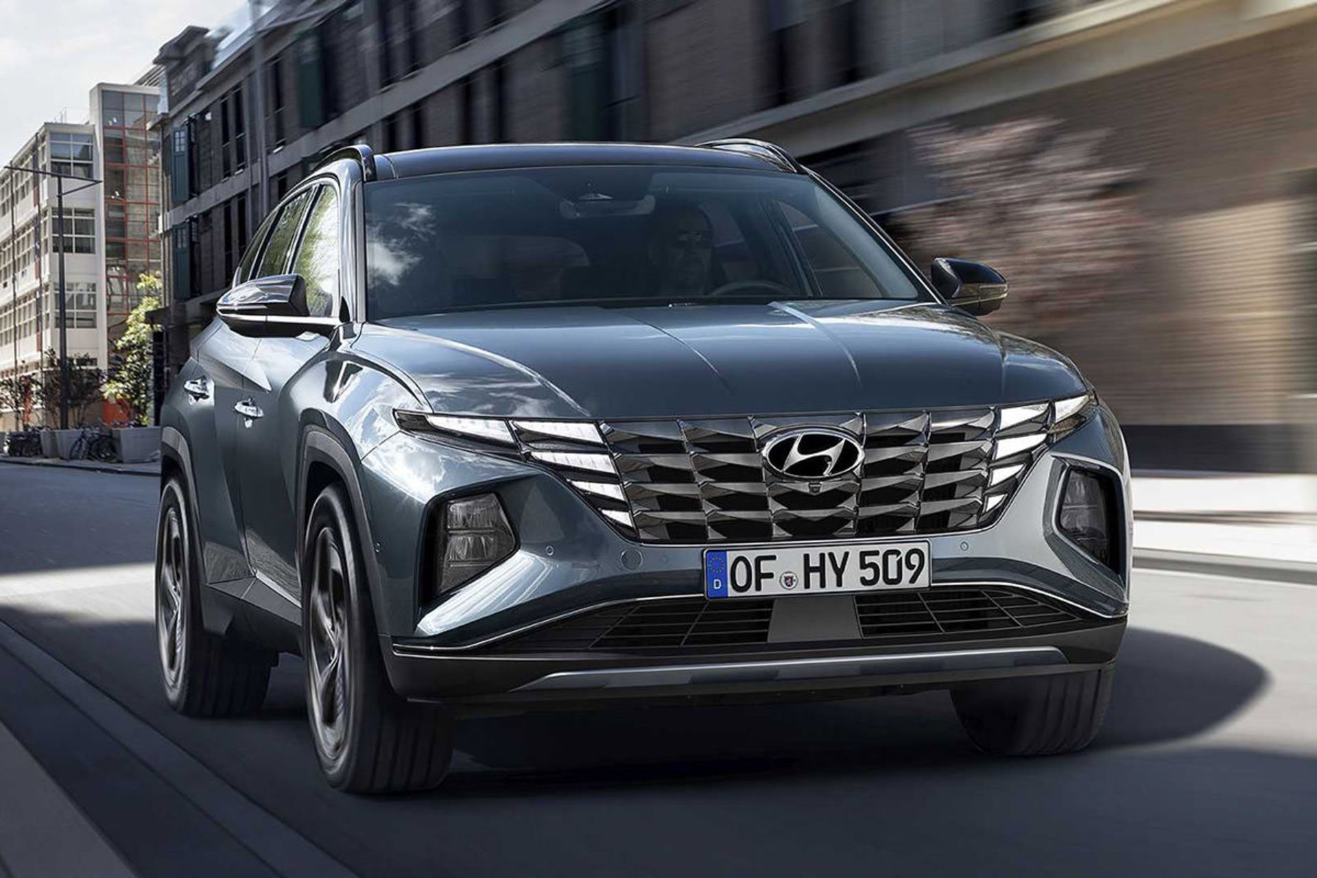 نمای اصلی خودرو کراس اور هیوندای توسان 2022 / 2022 Hyundai Tucson crossover با رنگ آبی در کنار ساختمان
