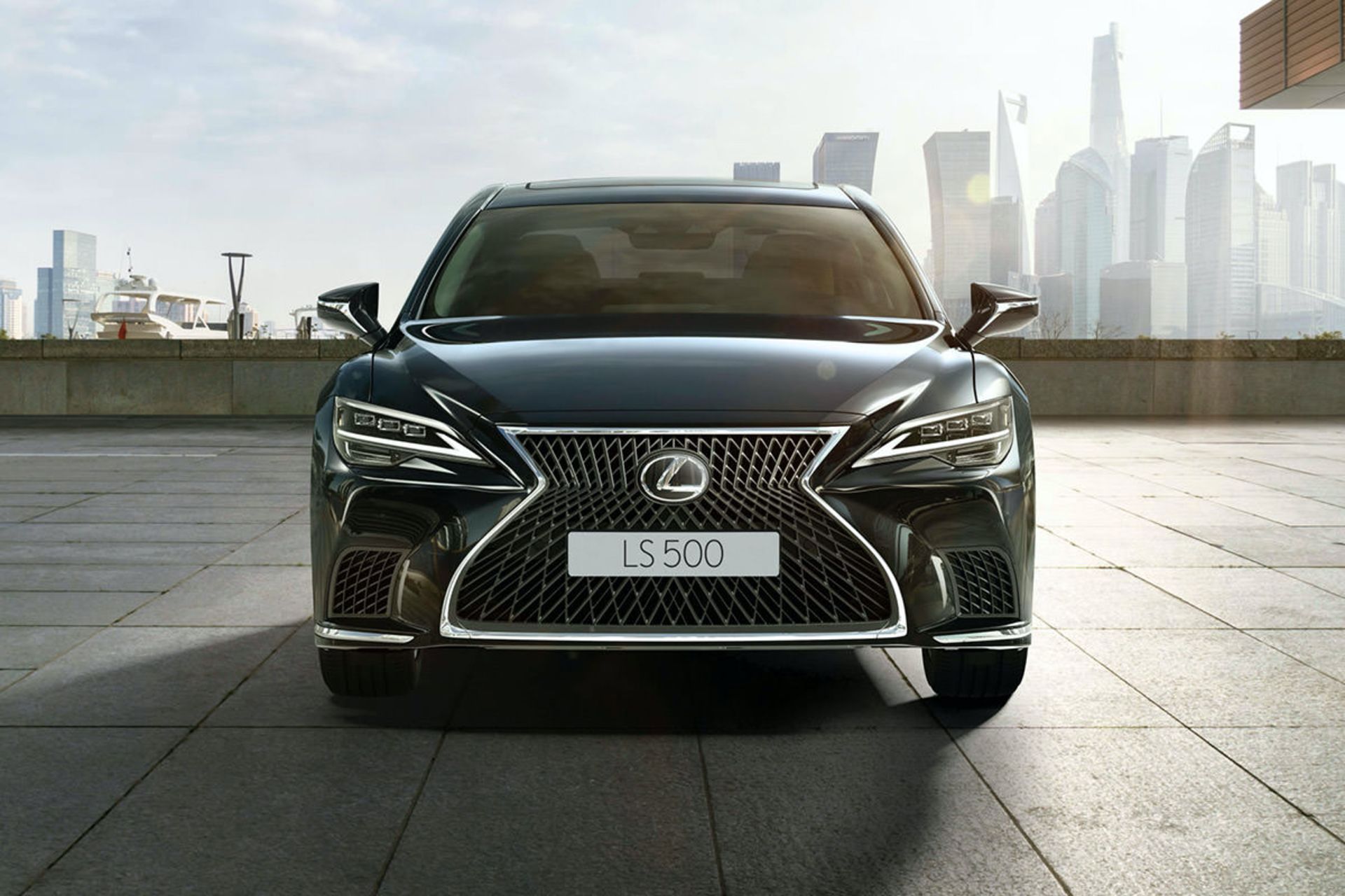 نمای جلو سدان پرچم دار لکسوس ال اس / 2021 Lexus LS مشکی رنگ با زمینه آسمان ابری و منظره آپارتمان در شهر