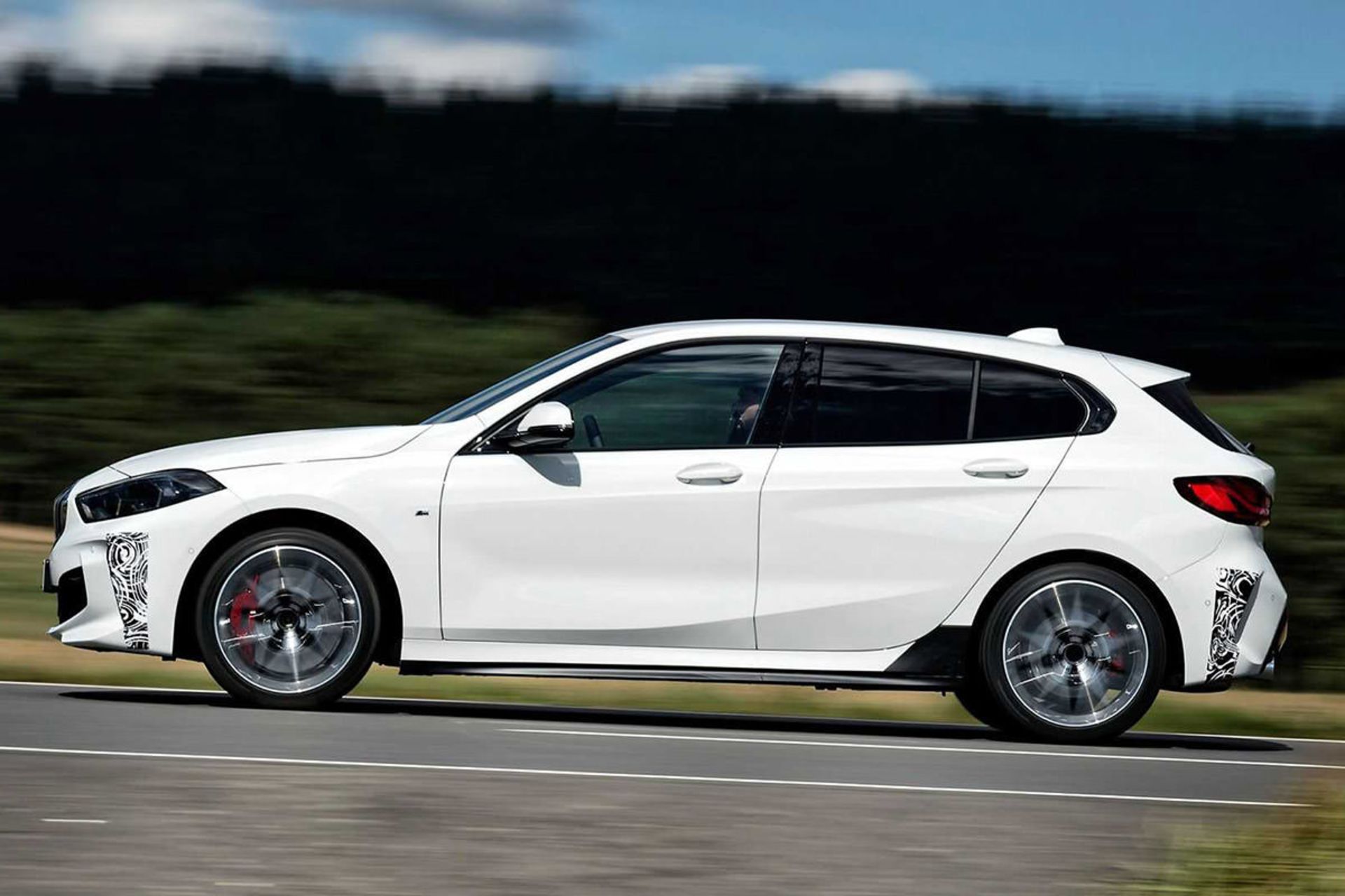 نمای جانبی هاچ بک بی ام و سری 1 / BMW 128ti سفید رنگ با منظره آسمان ابری و جنگل