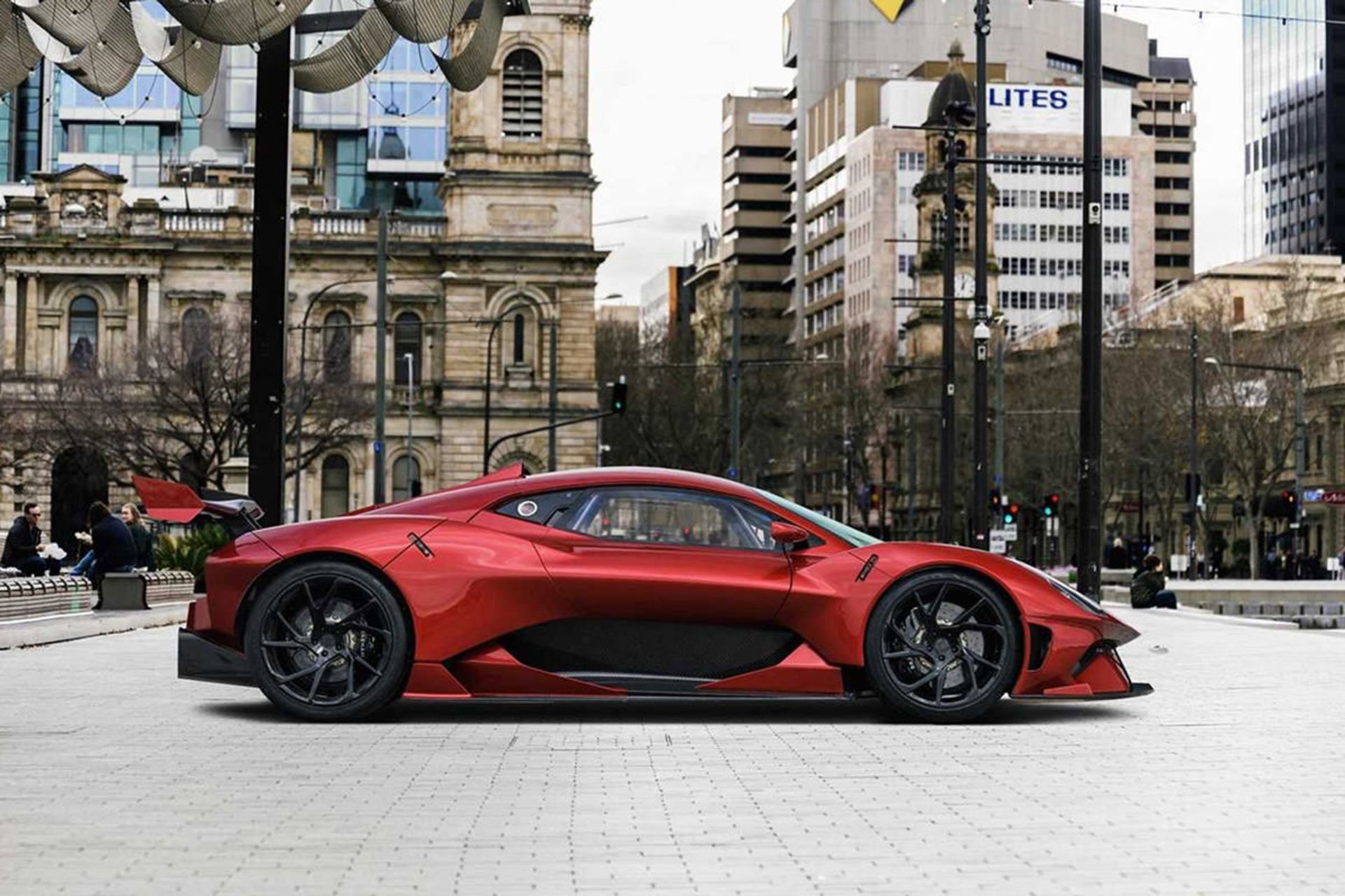 نمای جانبی خودرو سوپراسپرت برابهام / Brabham BT62R قرمز رنگ در خیابان و ساختمان