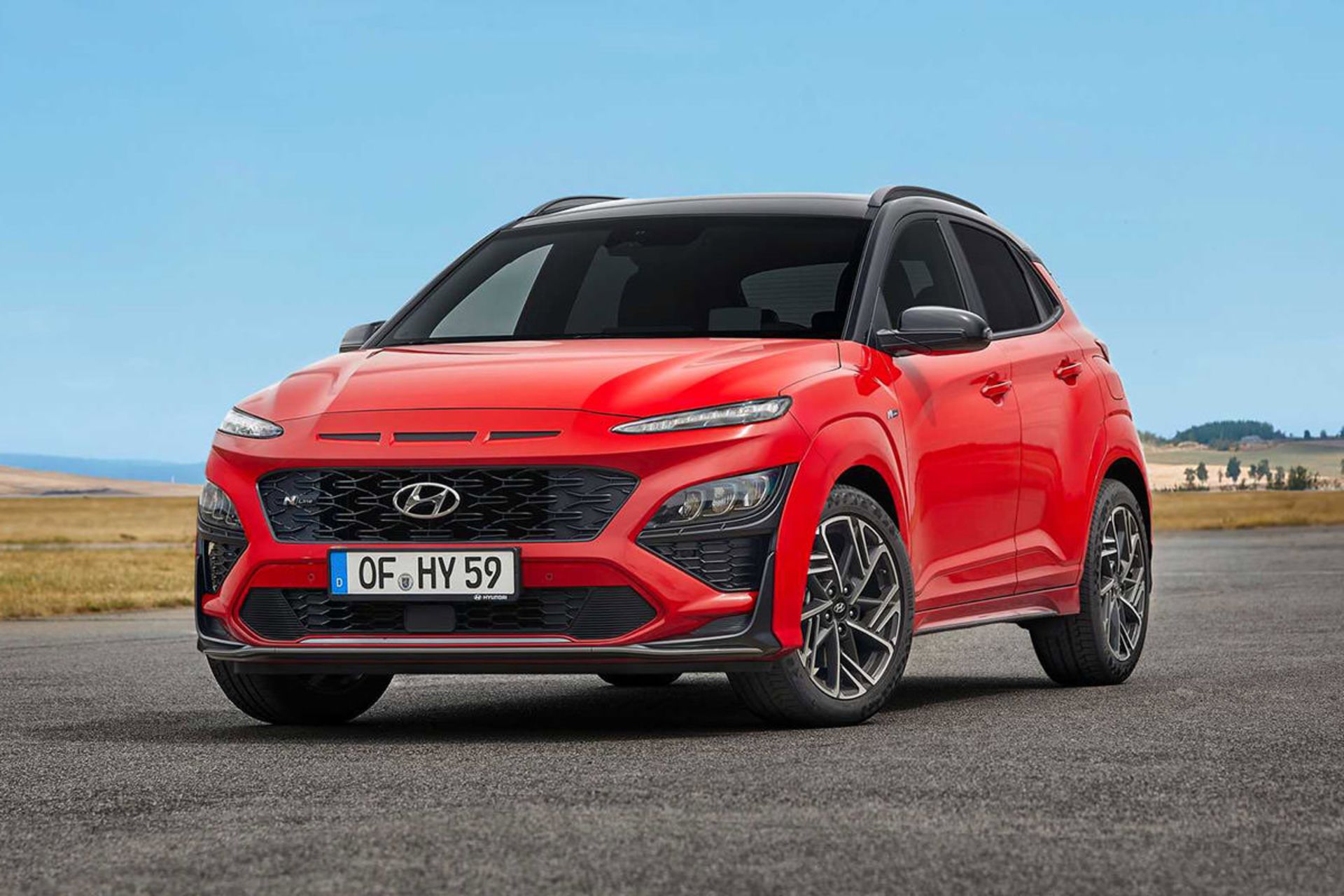 نمای سه چهارم جلو کراس اور هیوندای کنا ان لاین / Hyundai Kona N-Line crossover قرمز رنگ با زمینه آسمان آبی