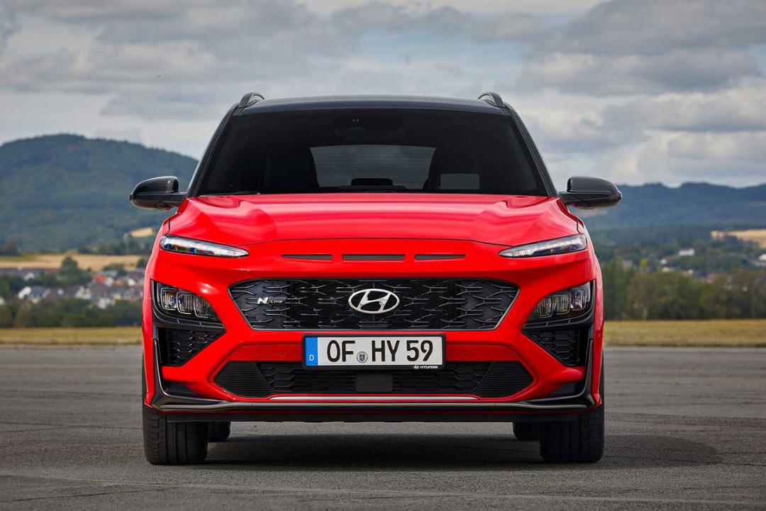 نمای جلو کراس اور هیوندای کنا ان لاین / Hyundai Kona N-Line crossover قرمز رنگ با زمینه آسمان ابری