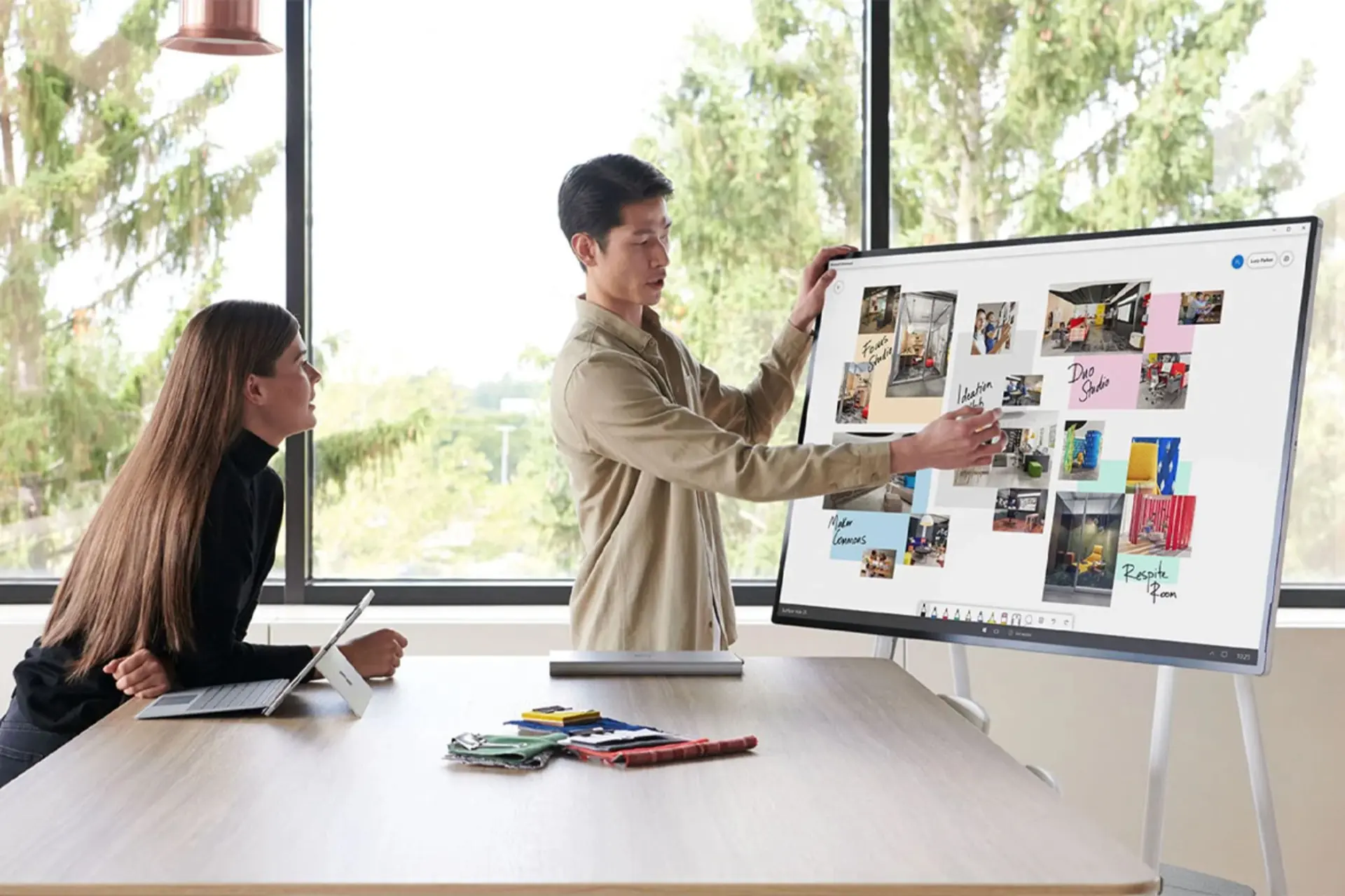 مرد درحال کار با سرفیس هاب 2 اس مایکروسافت / Microsoft Surface Hub 2S در اتاق با یک زن درخت سبز پنجره شفاف