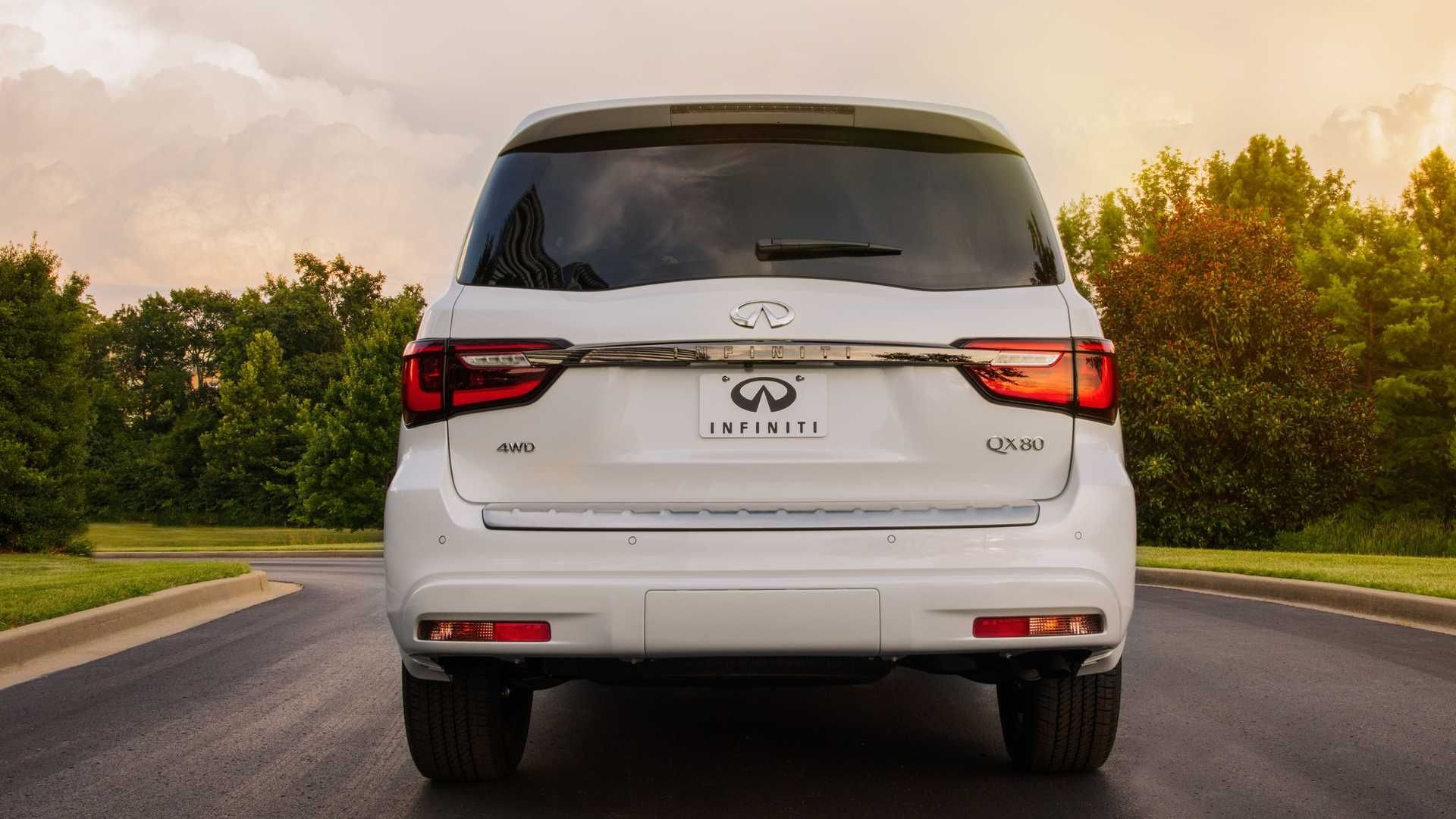 نمای عقب خودرو شاسی بلند لوکس اینفینیتی کیو ایکس 80 / 2021 Infiniti QX80 SUV سفید رنگ در جاده با زمینه درخت