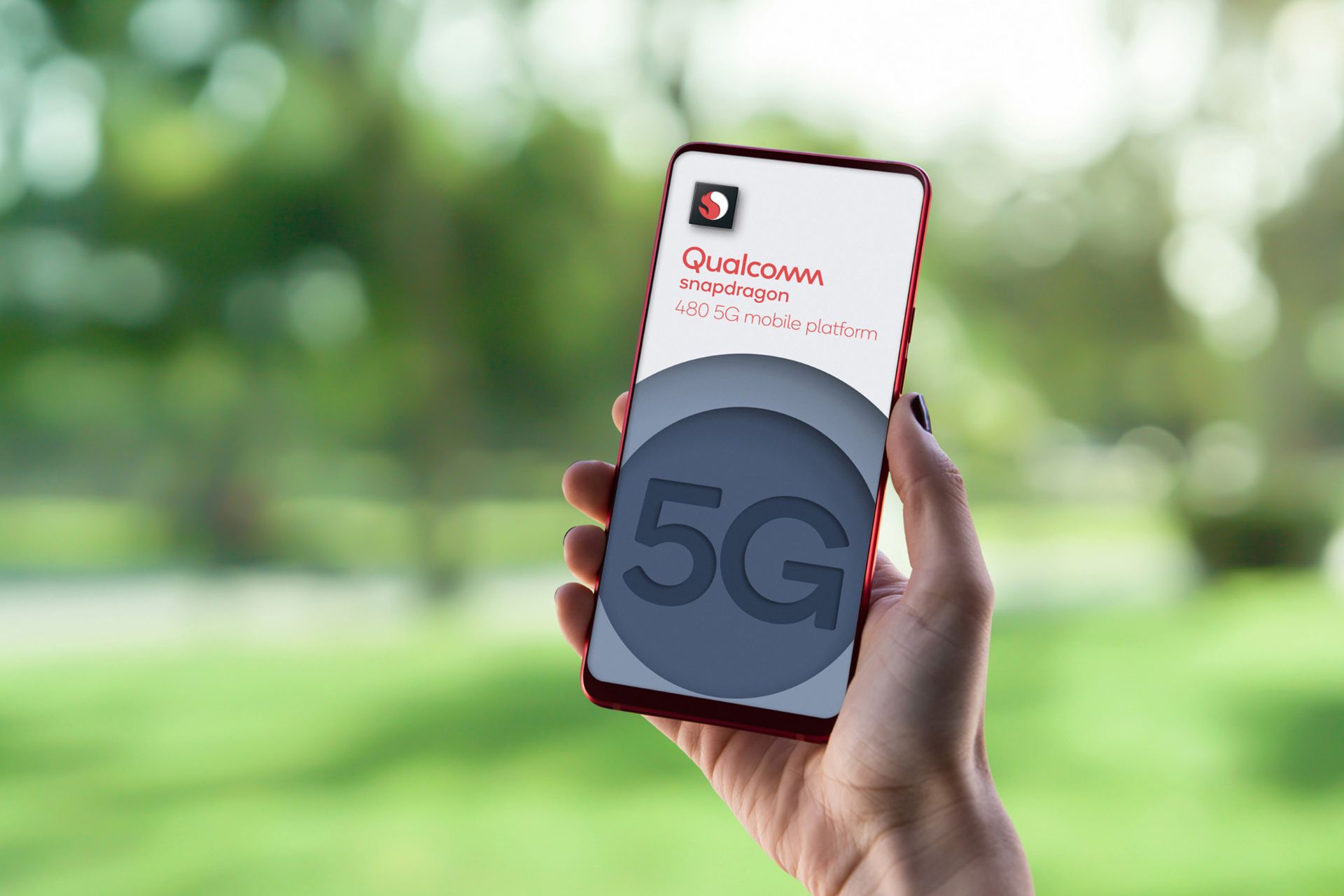 گوشی مجهزبه اسنپدراگون 480 (Snapdragon 480) در دست راست پس زمینه درخت و چمن