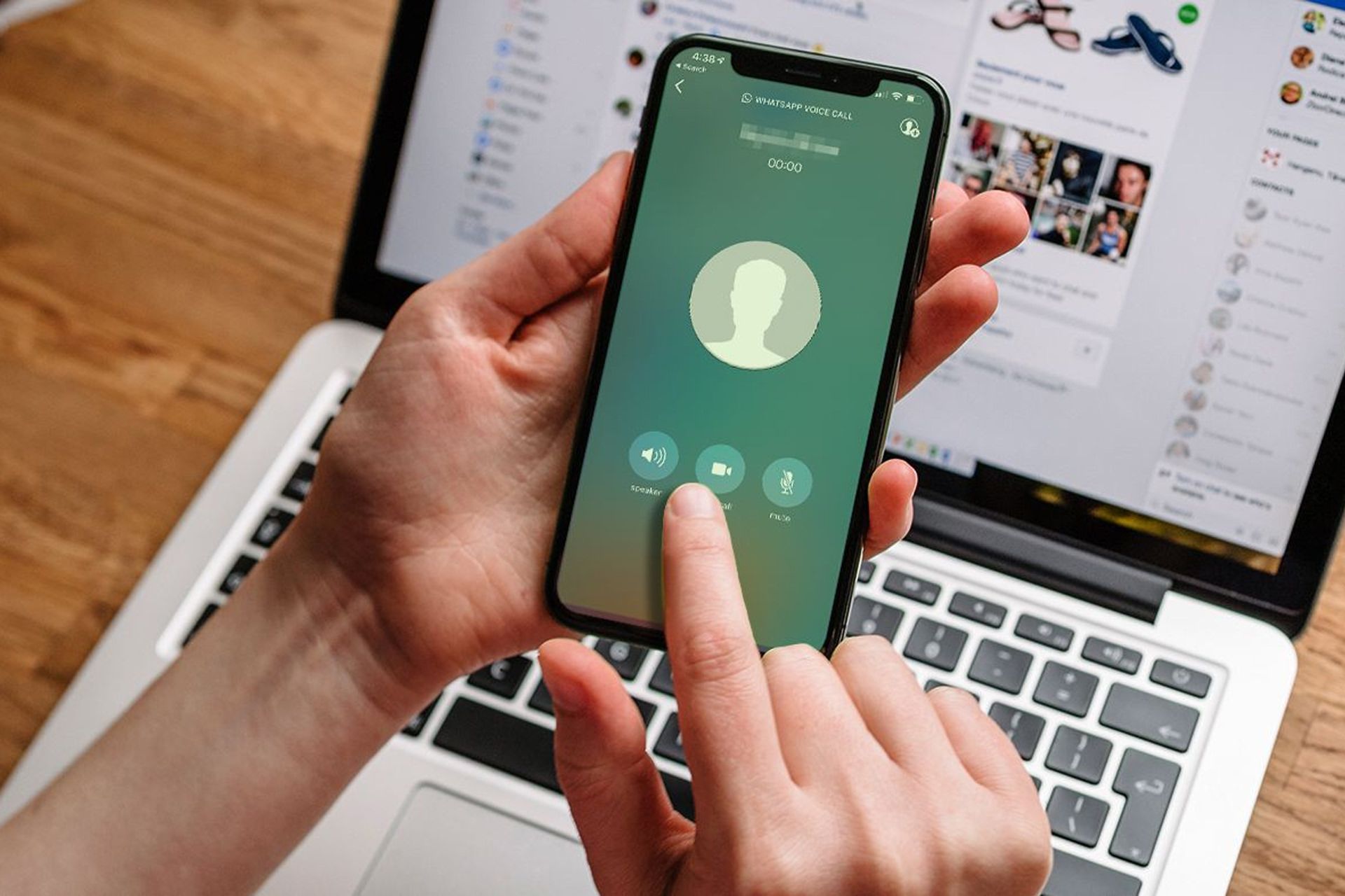 آیفون با واتساپ / WhatsApp در دست کاربر بالای لپ تاپ