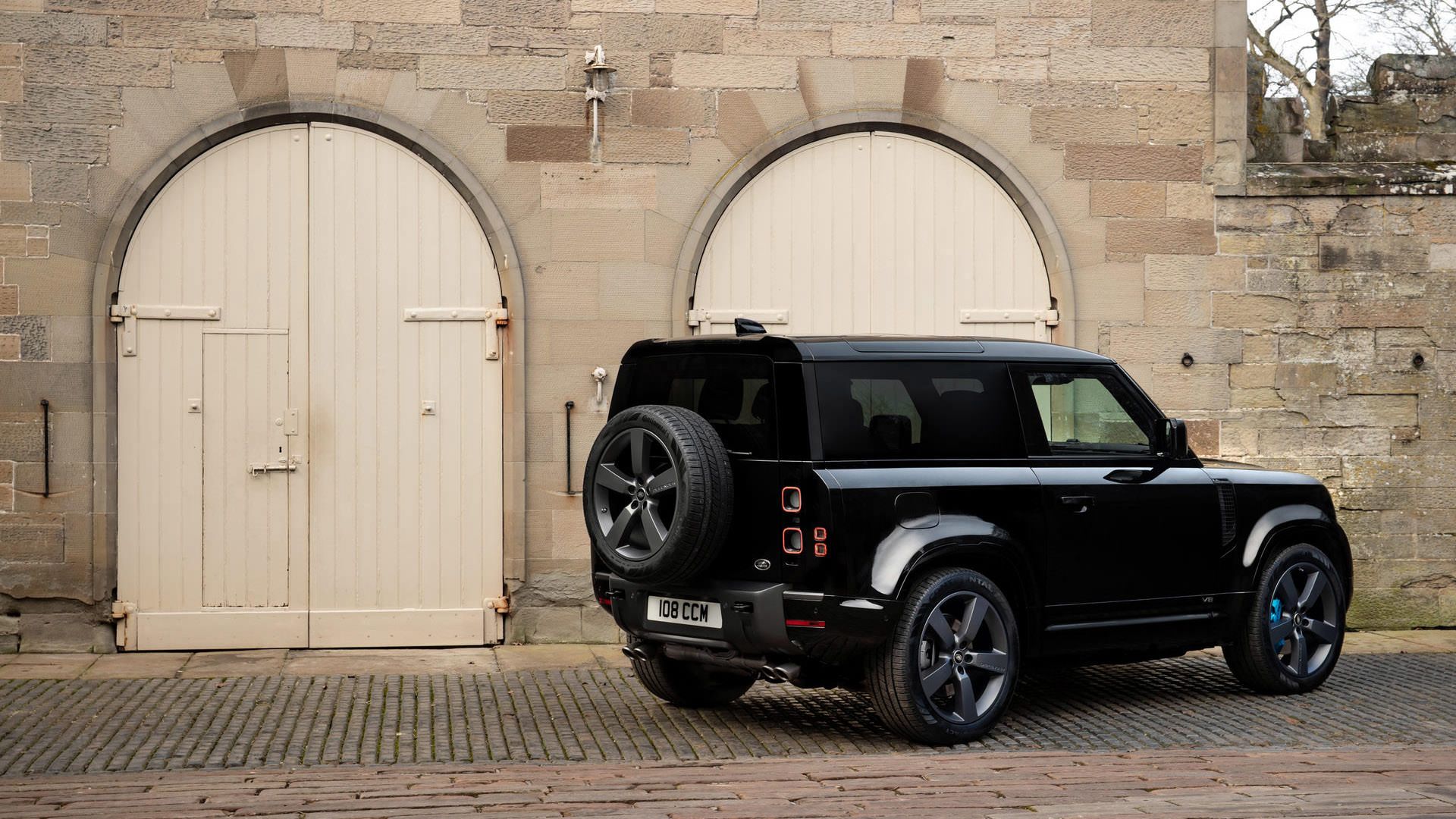 نمای عقب خودرو شاسی بلند لندرور دیفندر V8 / Land Rover Defender V8  در کنار ساختمان