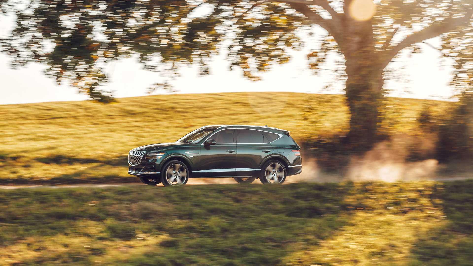 نمای جانبی خودرو شاسی بلند جنسیس جی وی 80 / 2021 Genesis GV80 رنگ مشکیدر جنگل با منظره درخت