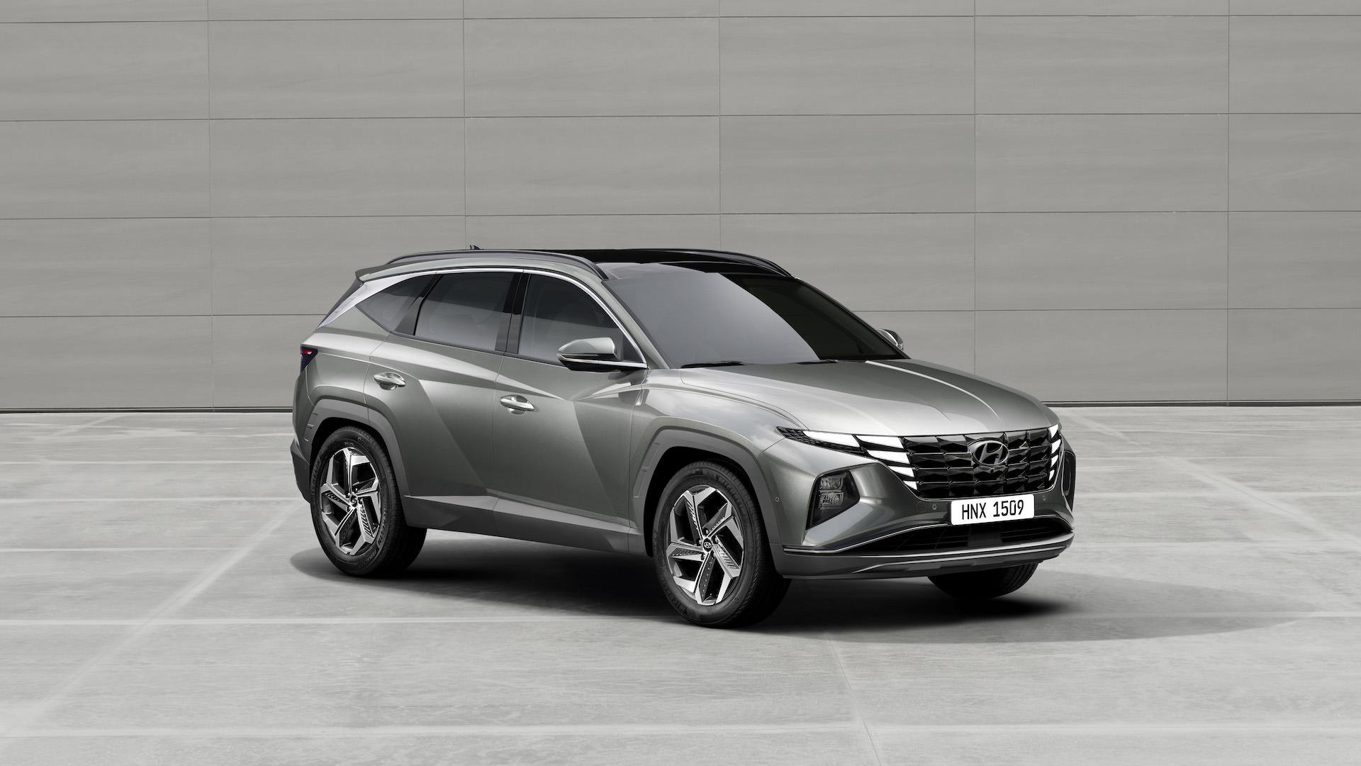 نمای سه چهارم کراس اور هیوندای توسان پلاگین هیبرید / 2022 Hyundai Tucson Plug-In Hybrid خاکستری رنگ در کنار ساختمان