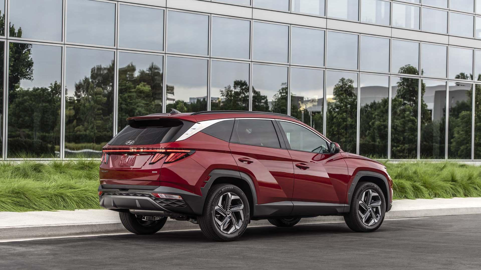 نمای عقب کراس اور هیوندای توسان پلاگین هیبرید / 2022 Hyundai Tucson Plug-In Hybrid قرمز رنگ در کنار ساختمان