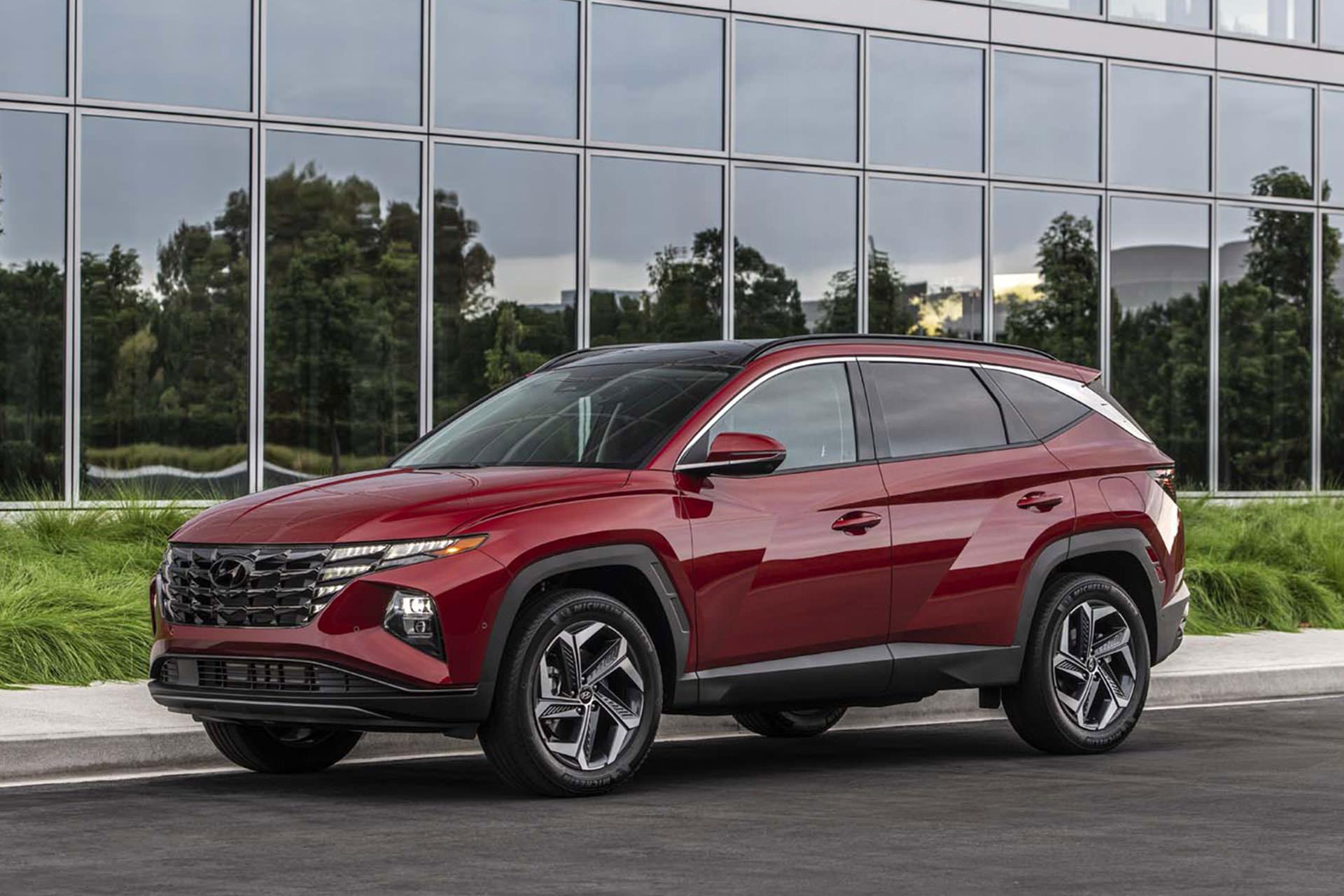 نمای کراس اور هیوندای توسان پلاگین هیبرید / 2022 Hyundai Tucson Plug-In Hybrid قرمز رنگ در کنار ساختمان شیشه ای 