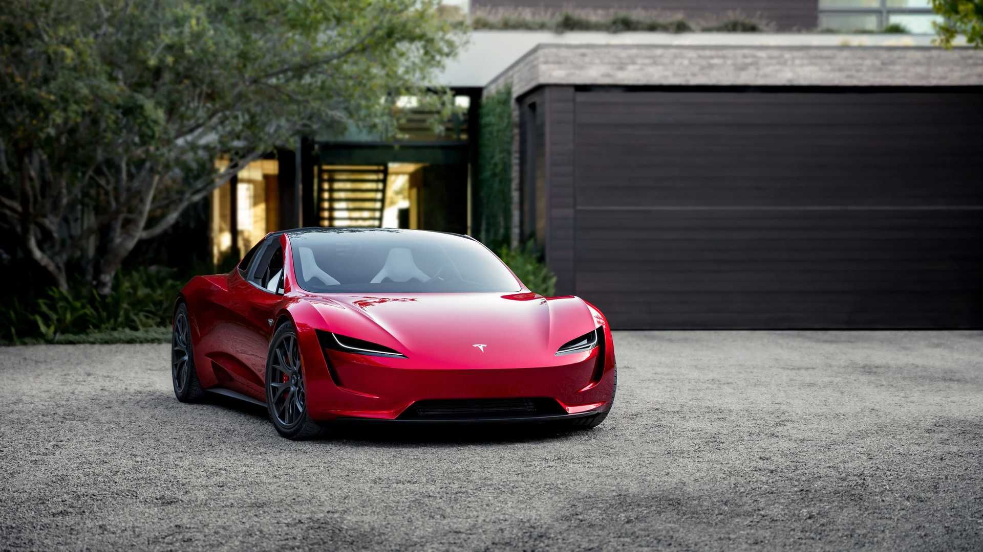 نمای جلو خودروی الکتریکی تسلا رودستر / Tesla Roadster قرمز رنگ در کنار خانه و  درخت