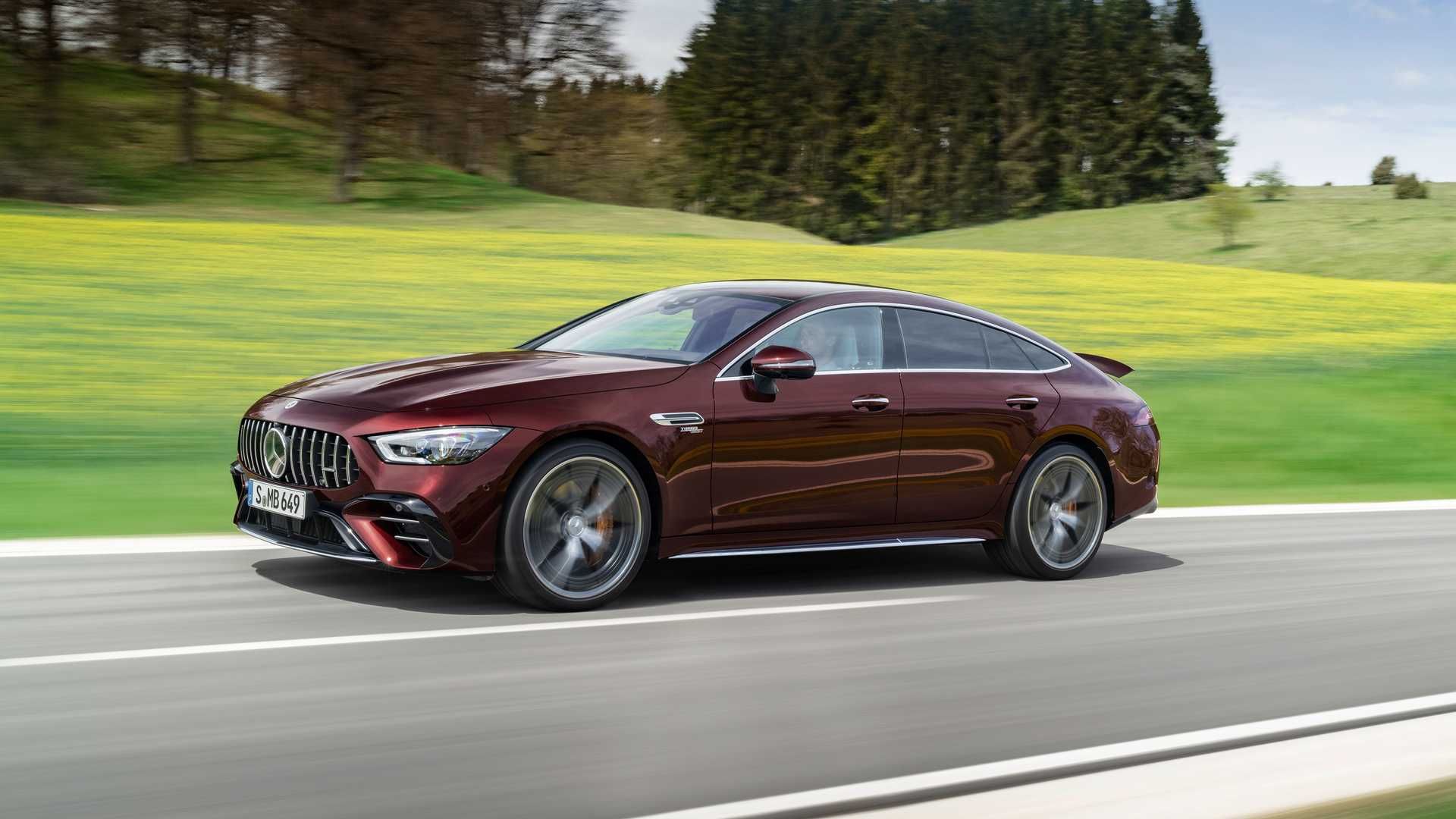 نمای سه چهارم مرسدس آ ام گ جی تی چهاردر / 2022 Mercedes-AMG GT 4-Door قرمز رنگ در جاده با منظره درخت